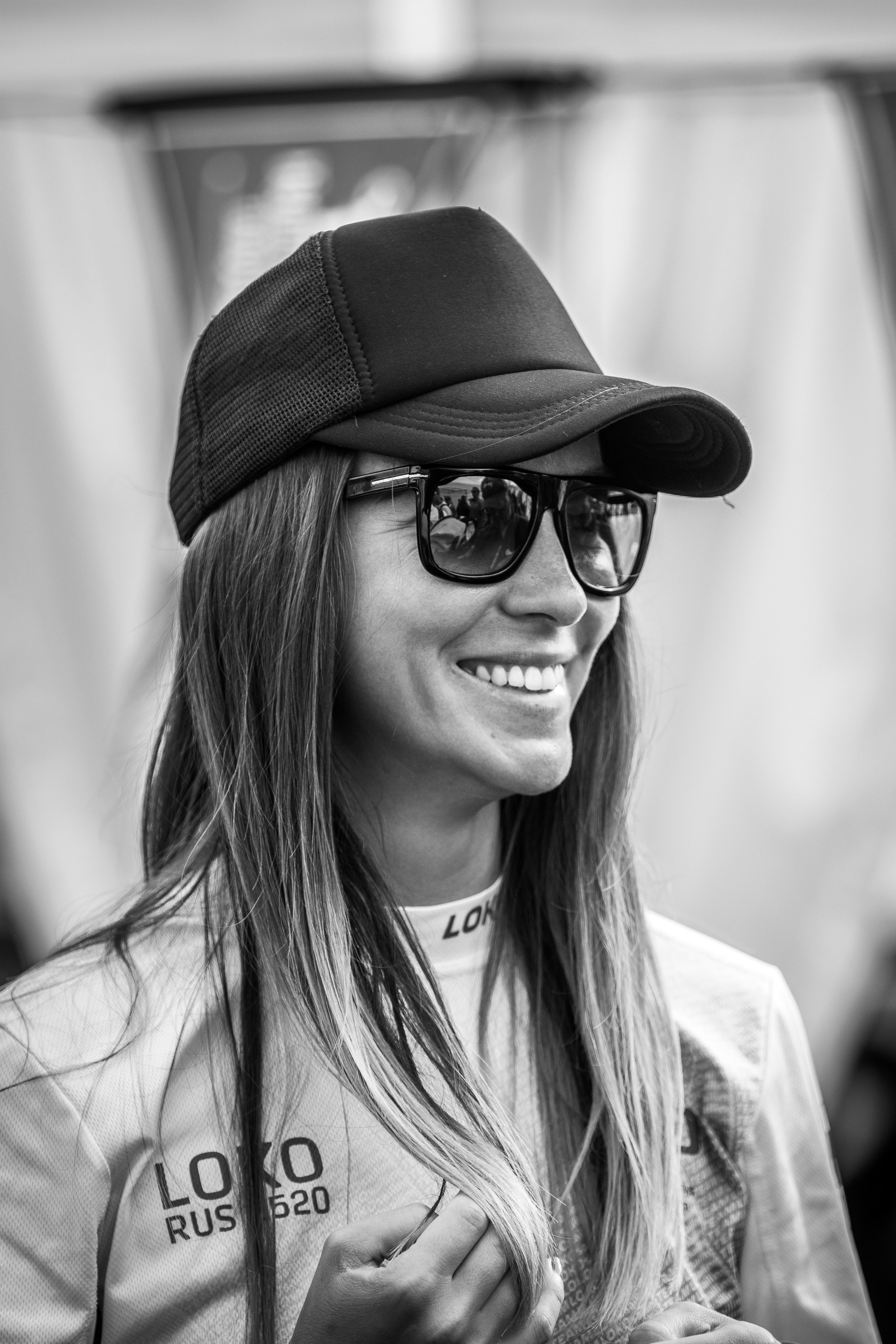 Красивая девушка в кепке и очках, яхтсменка на корпоративной парусной регате. Монохромный репортажный портрет.