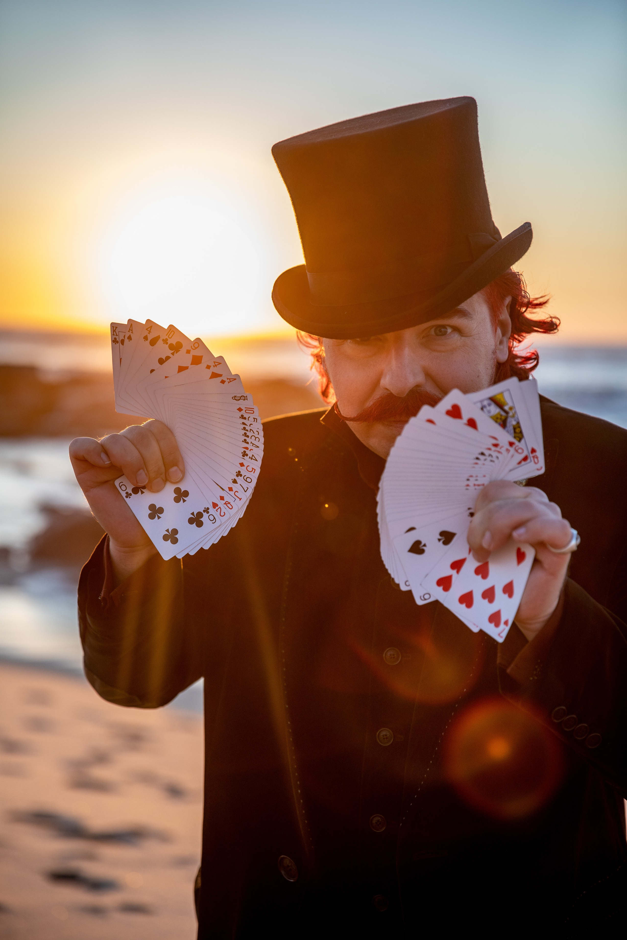 Illusionist and magician walks on the beach and shows tricks. Photo shoot for a magician with a red moustache