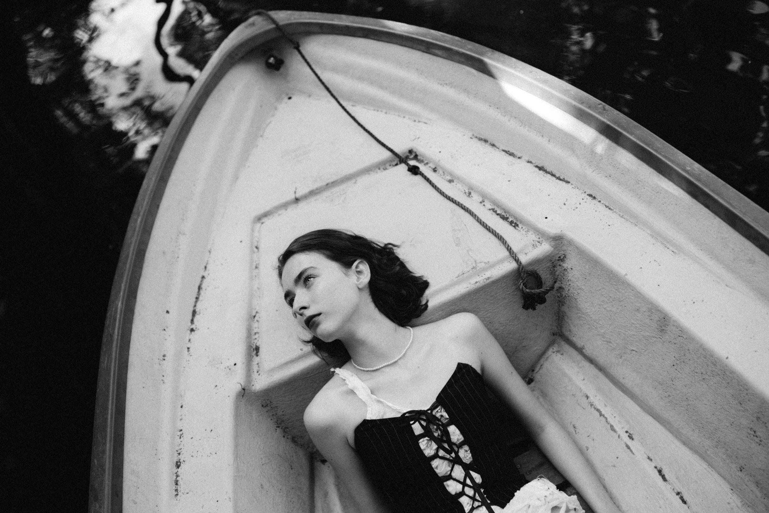 Девушка с темными волосами лежит в лодке и смотри вверх