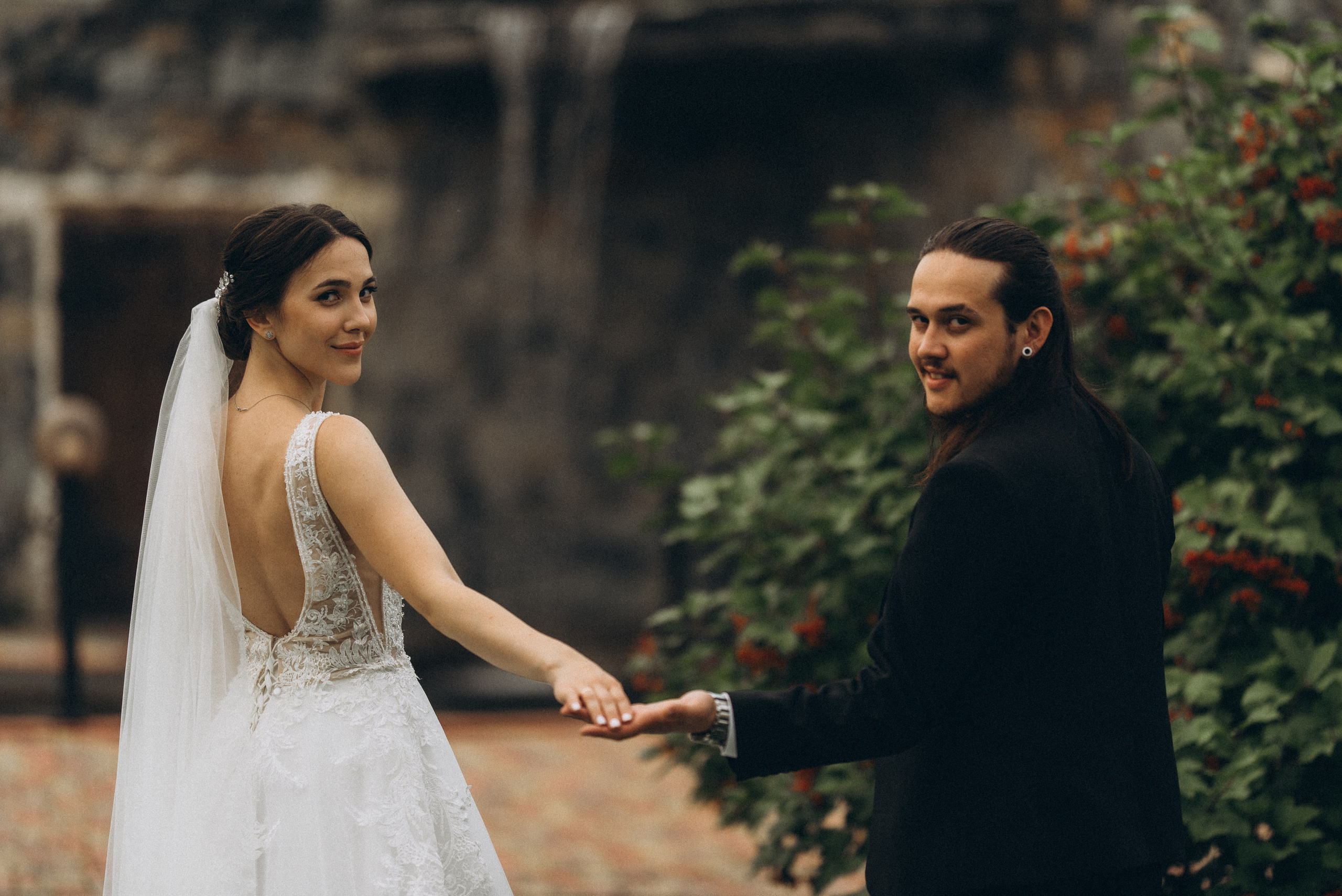 Невеста Линда и жених Никита оглядываются через плечо, держась за руки. Свадебная прогулка в Новосибирске.