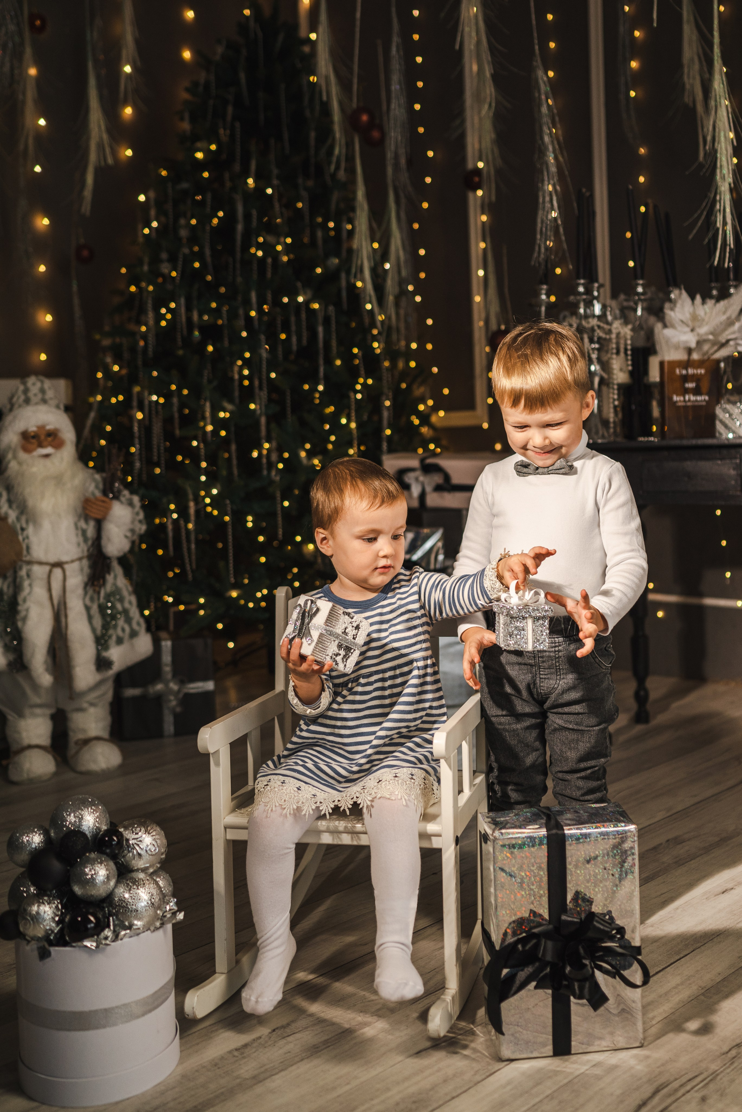 Детская семейная новогодняя фотосессия 2025 в фотостудии в Каменске-Шахтинском и Ростове-на-Дону. Двое маленьких детей сидят на фоне новогодней елки. Фотограф Ольга Сагал 
