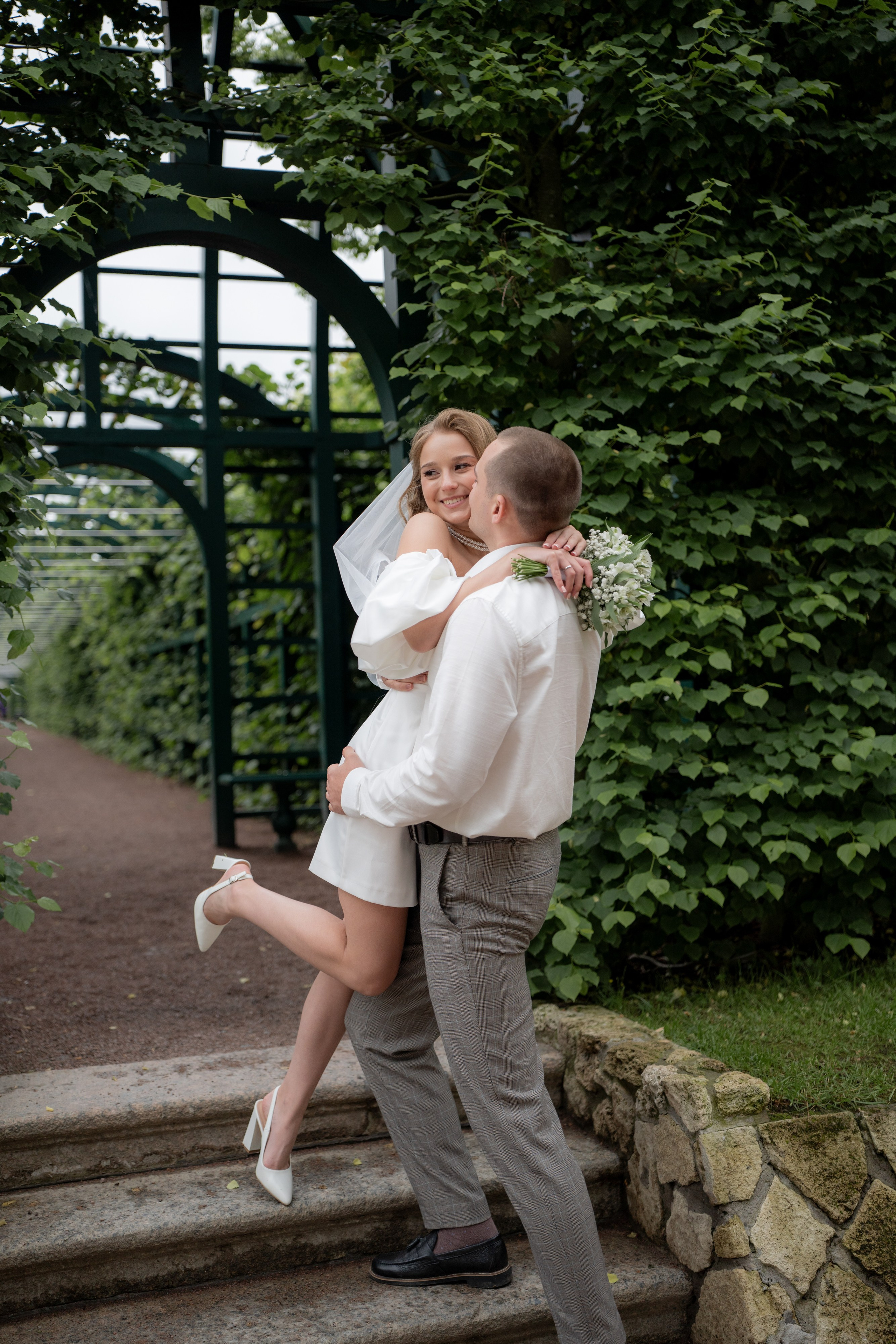 Свадебная фотосессия в Верхнем парке Петергофа. Невеста обнимает жениха на лестнице