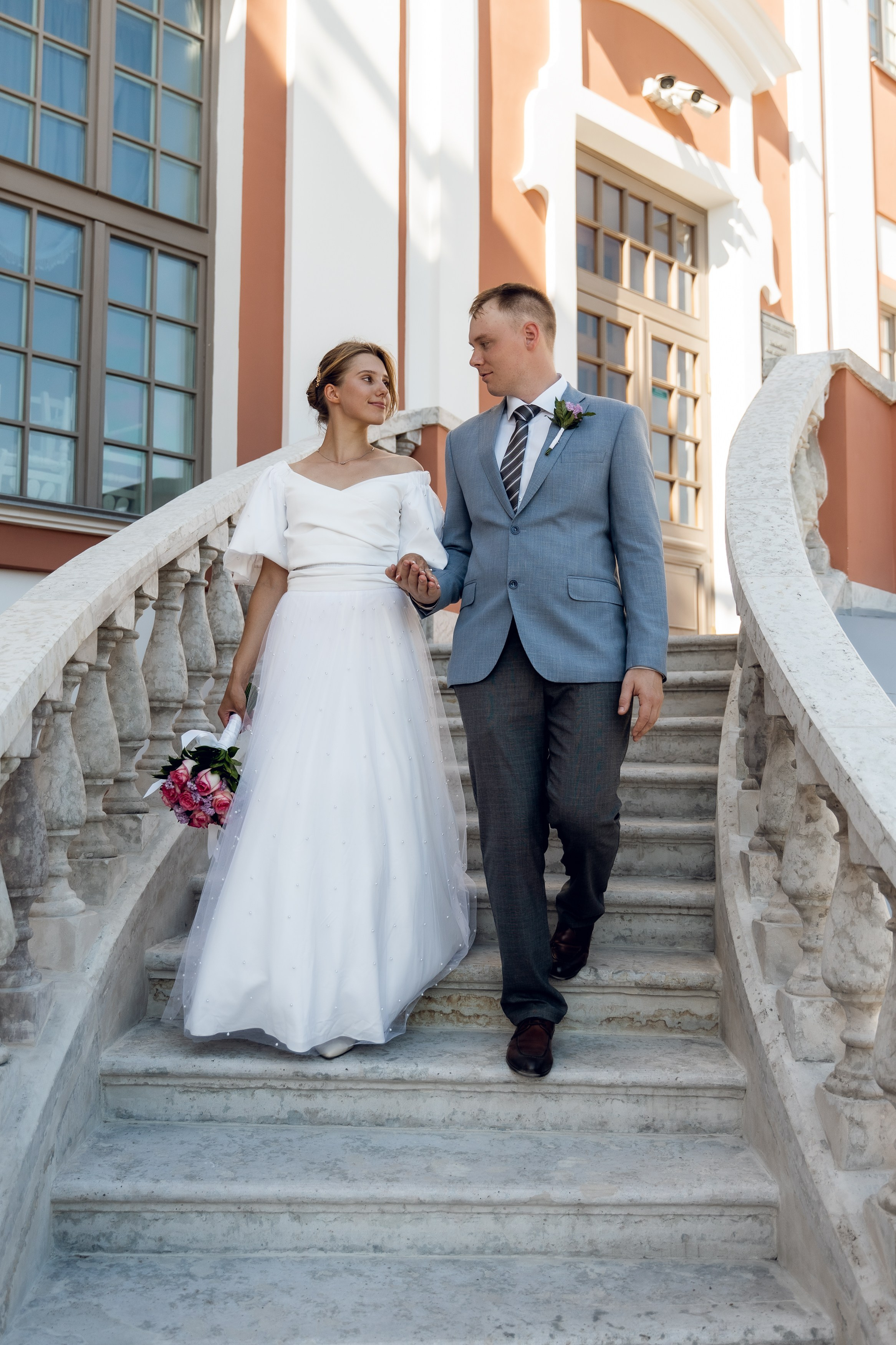 Жених и невеста спускаются по лестнице Кикиных палат на свадебной фотосессии