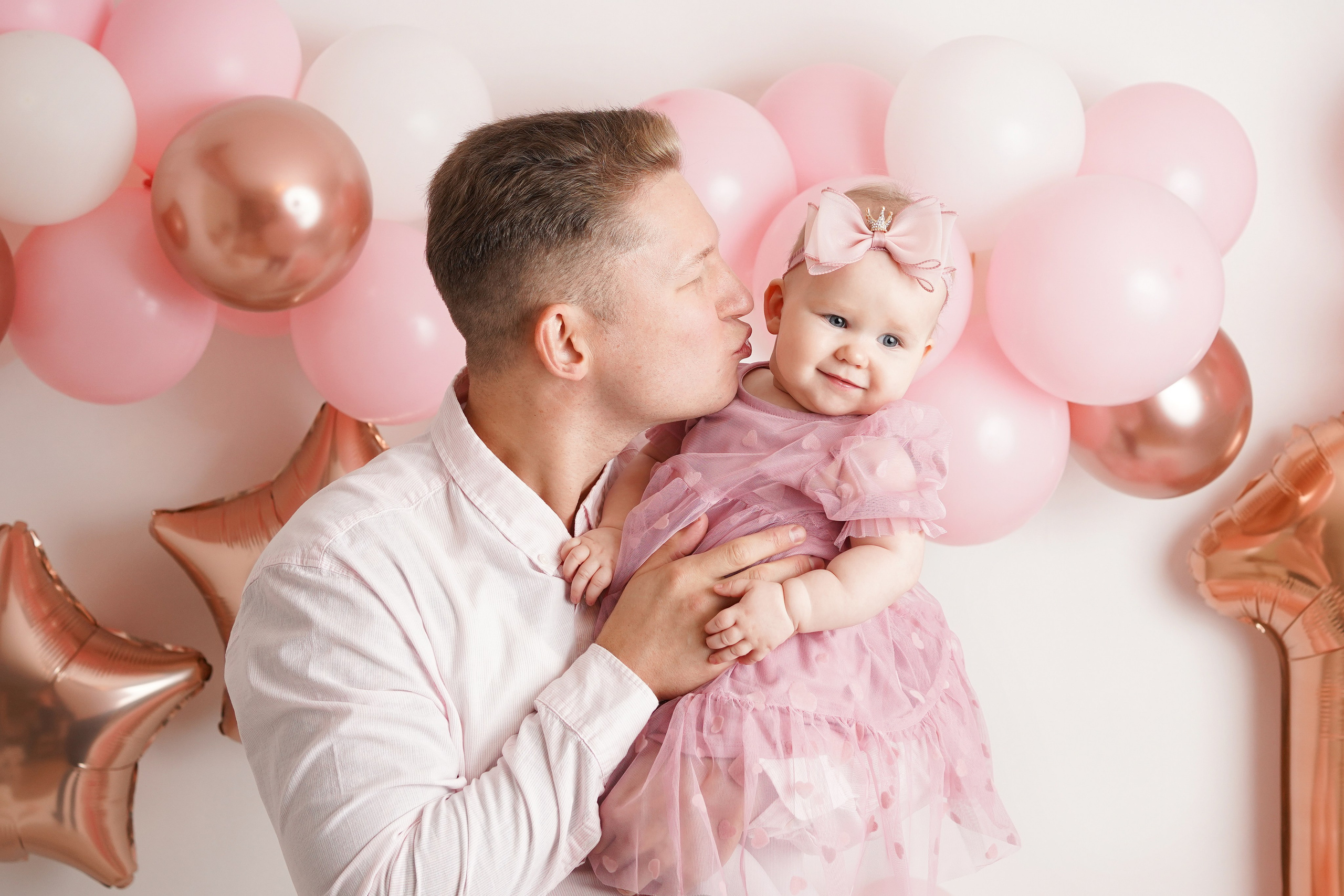 На фото малышка у папы на руках. Папа целует ее в щечку.