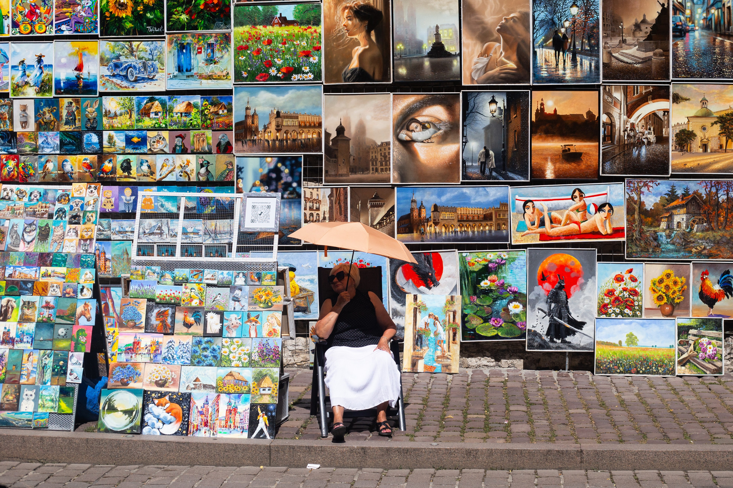The painting seller is hiding from the sun.