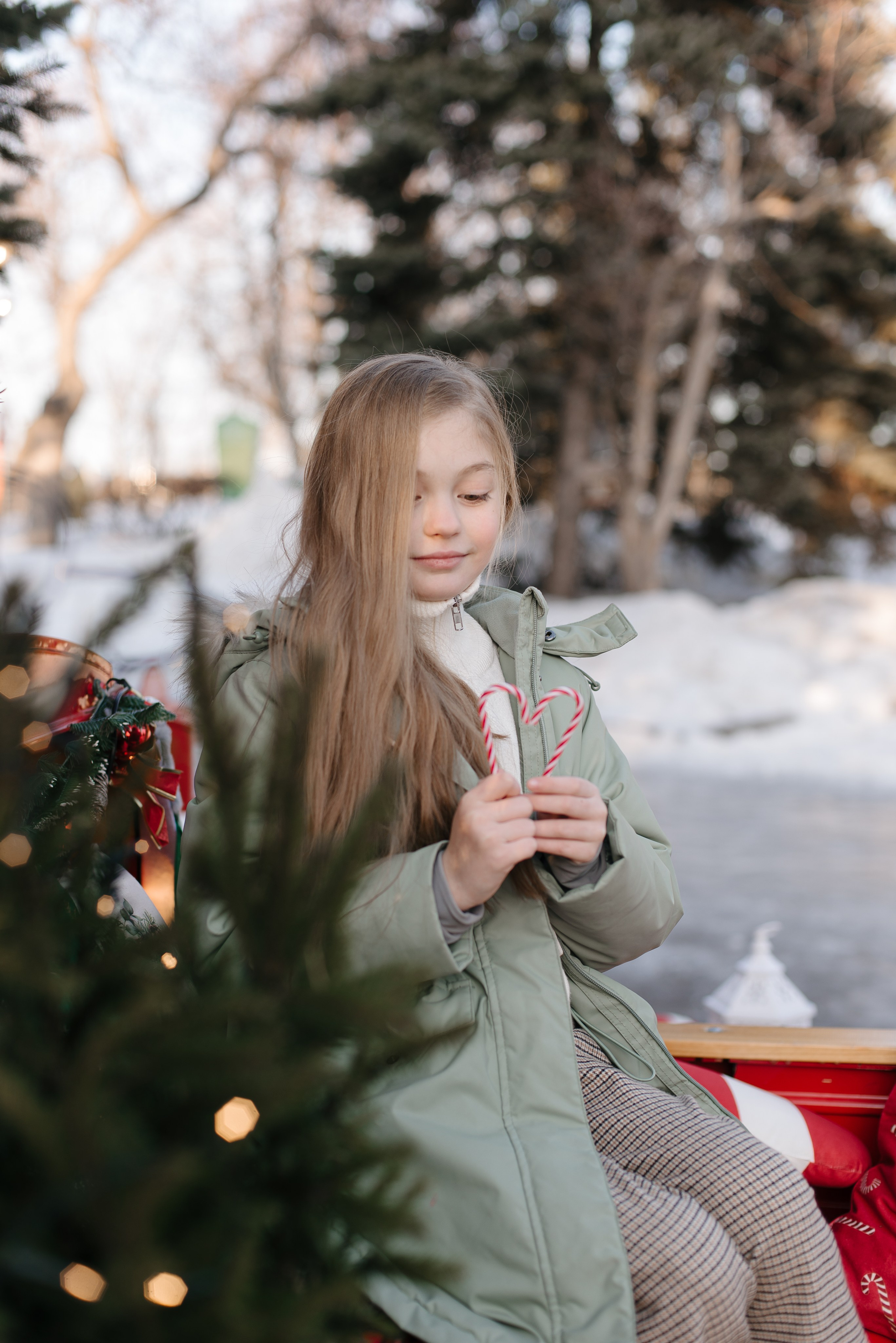 Девочка в зеленой куртке держит леденец.
