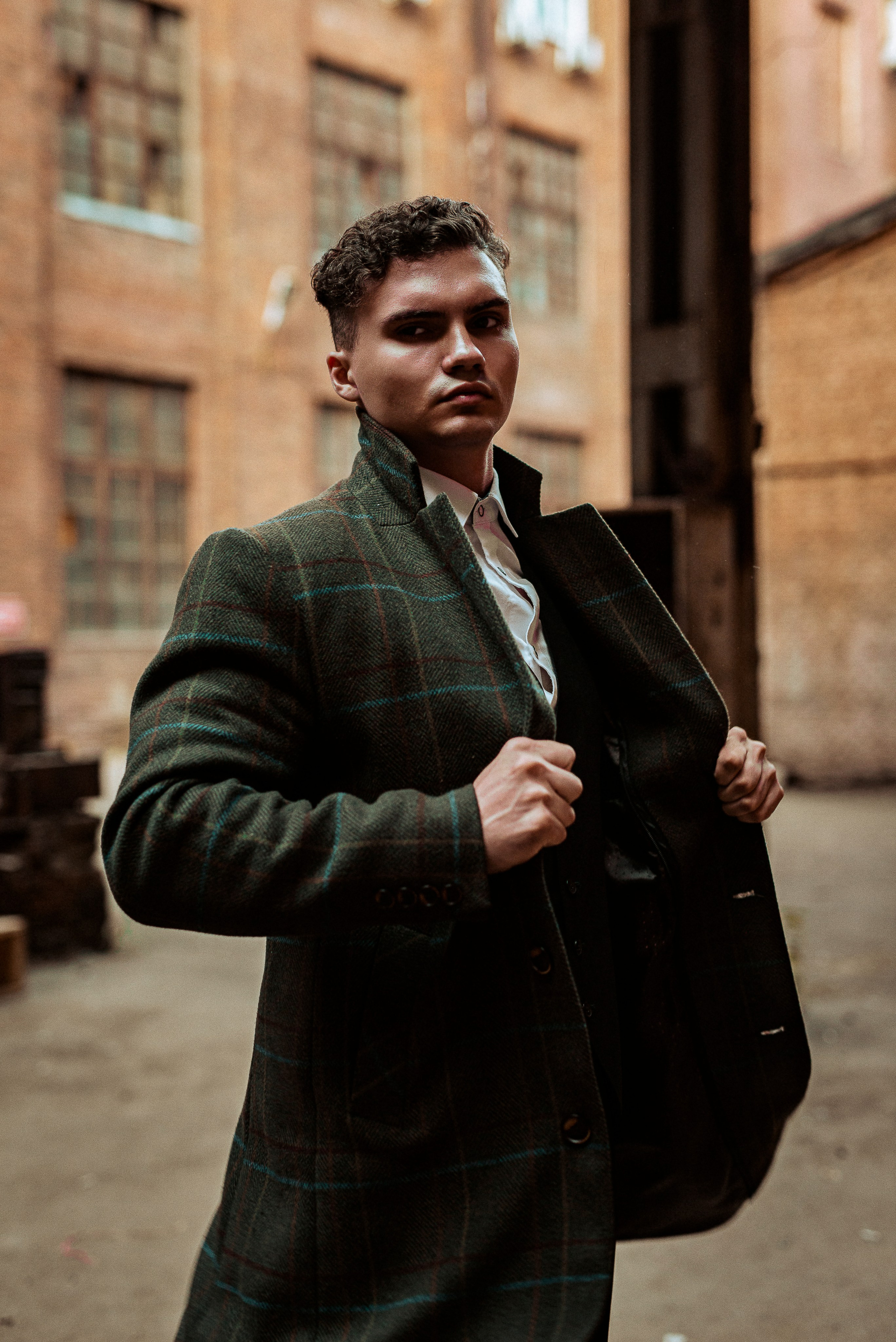 Молодой человек запечатлён на фоне здания из красного кирпича.