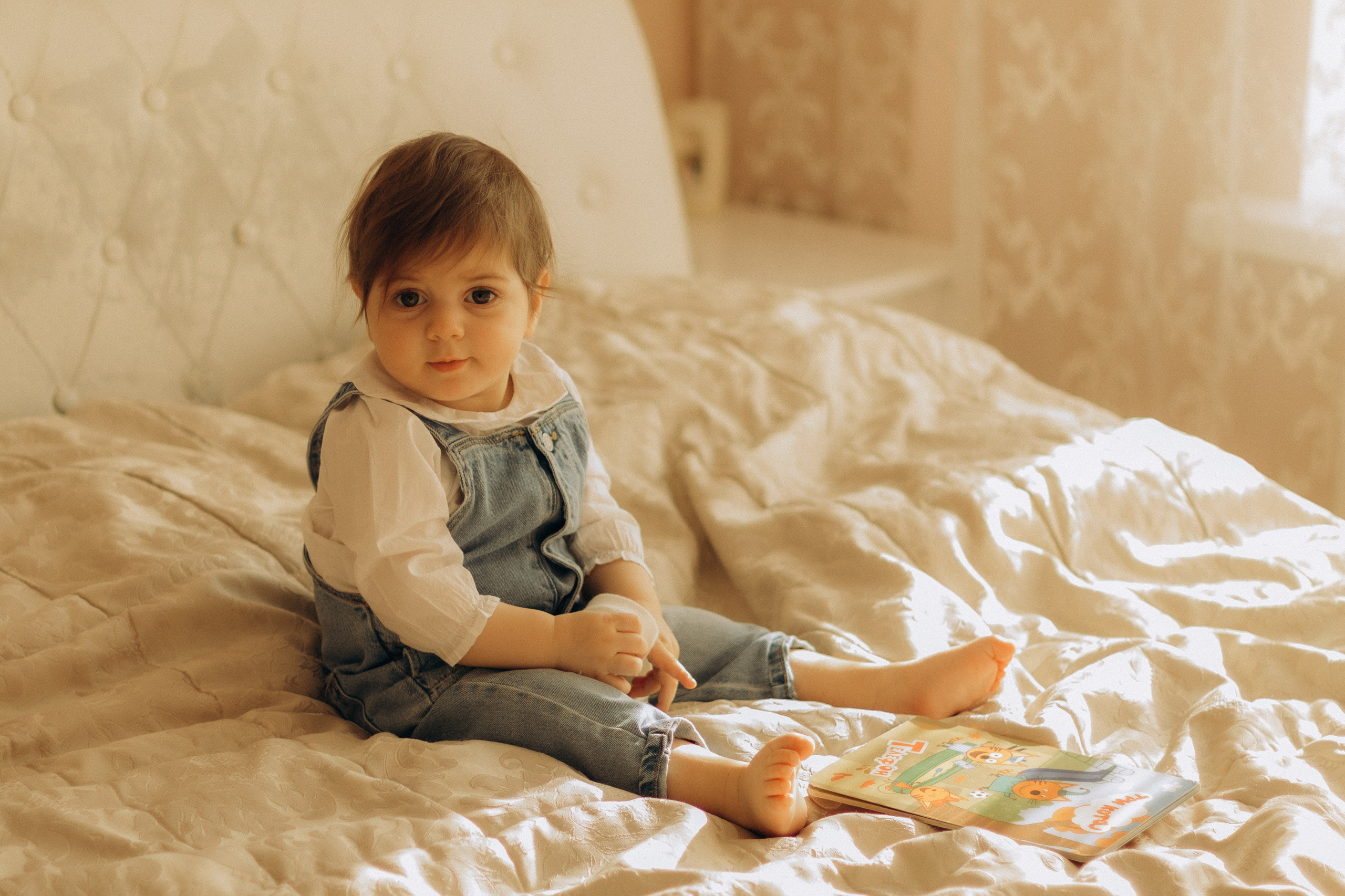 Маленькая девочка сидит на кровати, детская фотосессия