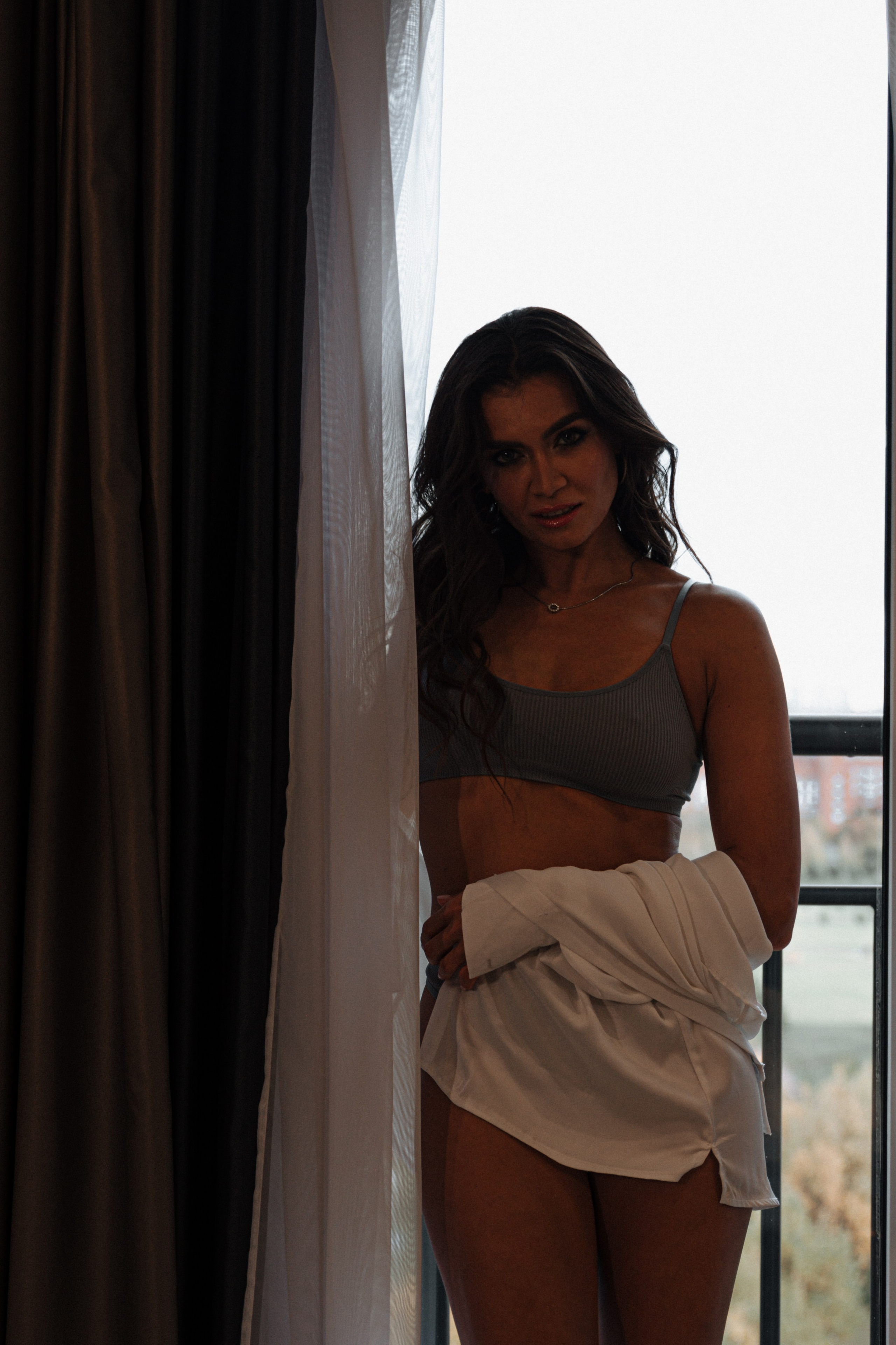 "Стильная, обворожительная гостья отеля великолепно демонстрирует свою привлекательность в завораживающем белье и элегантной рубашке."