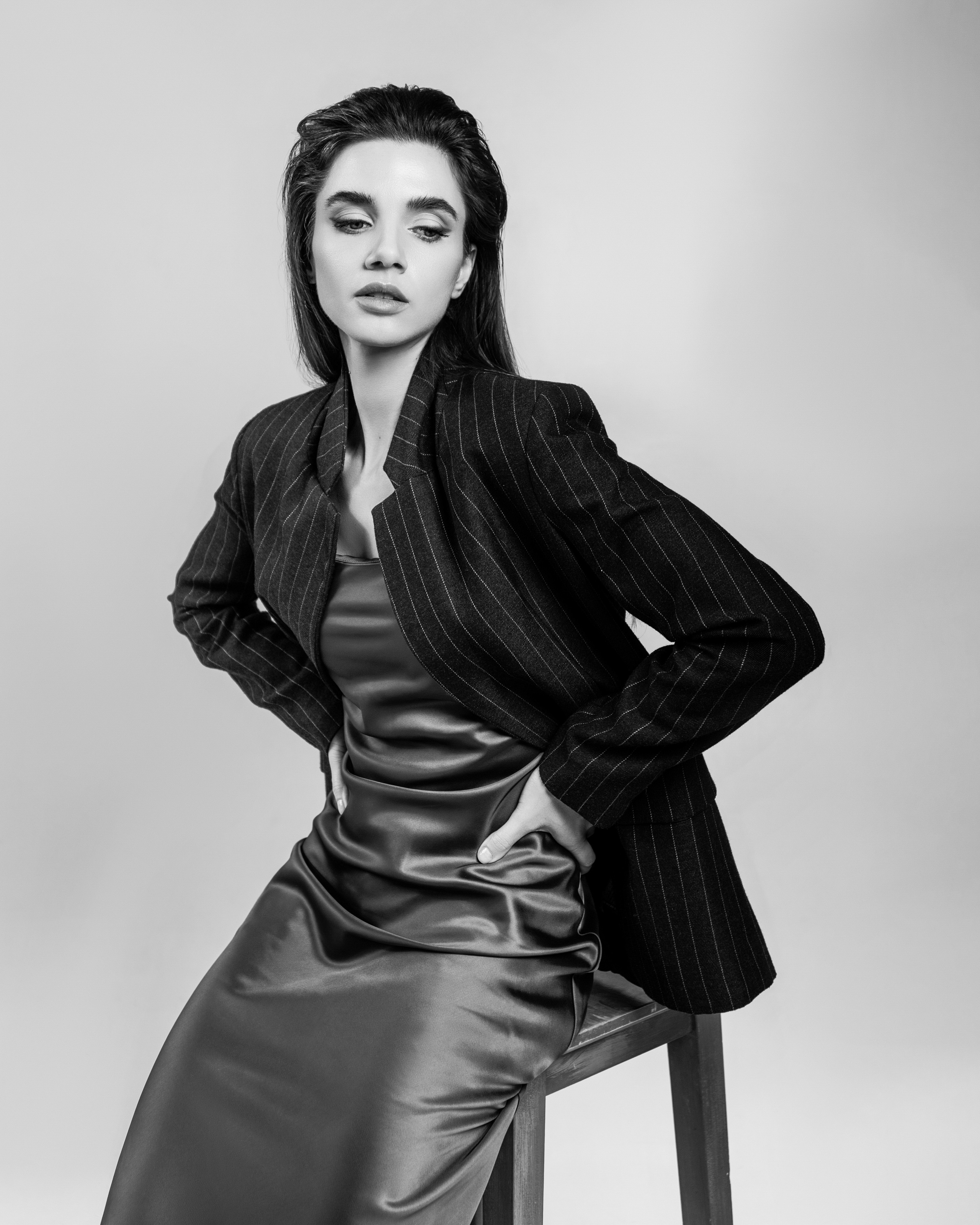 Чёрно-белый женский портрет на высоком стуле в студии