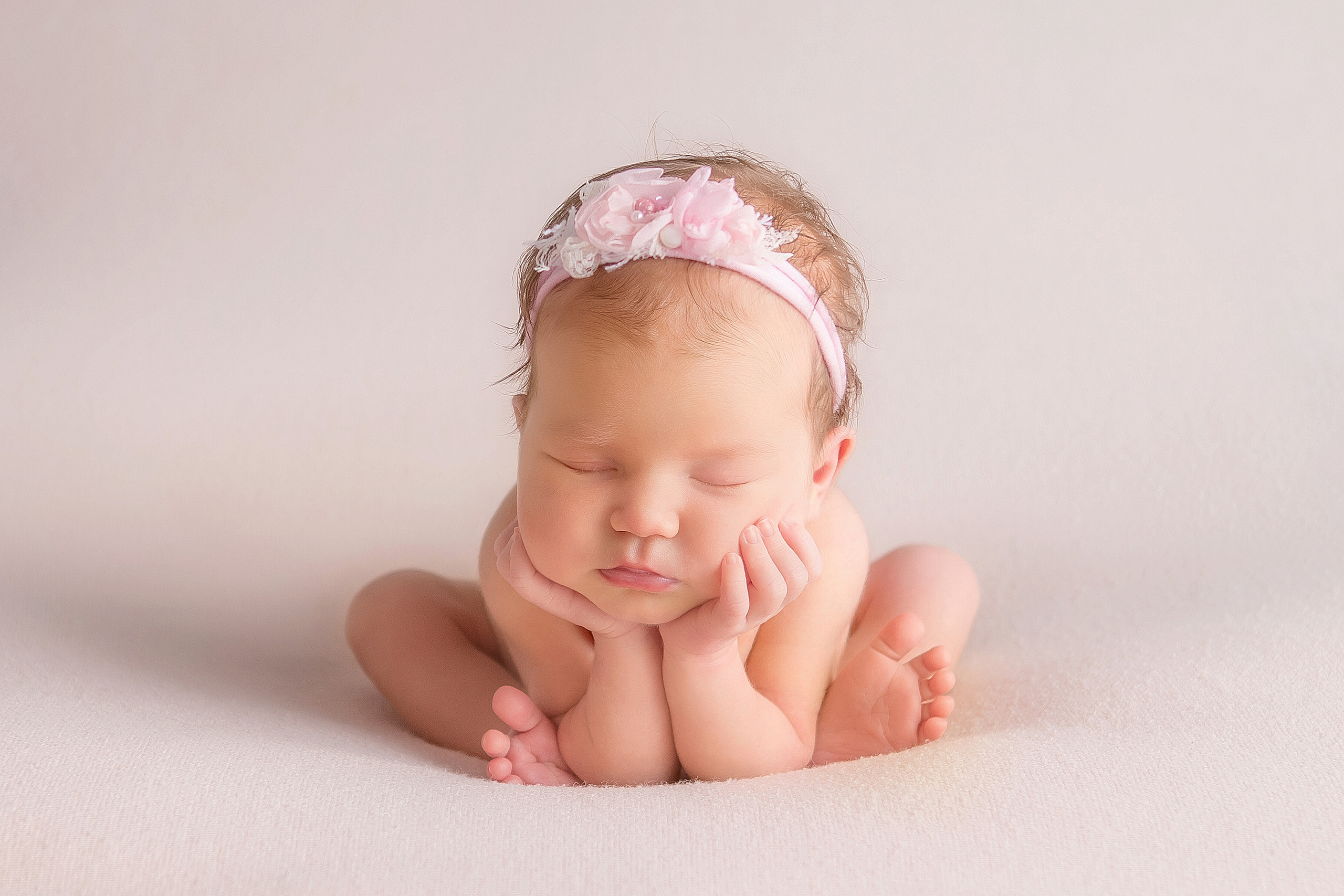 новорожденная малышка в розовом ободочке в позе лягушки