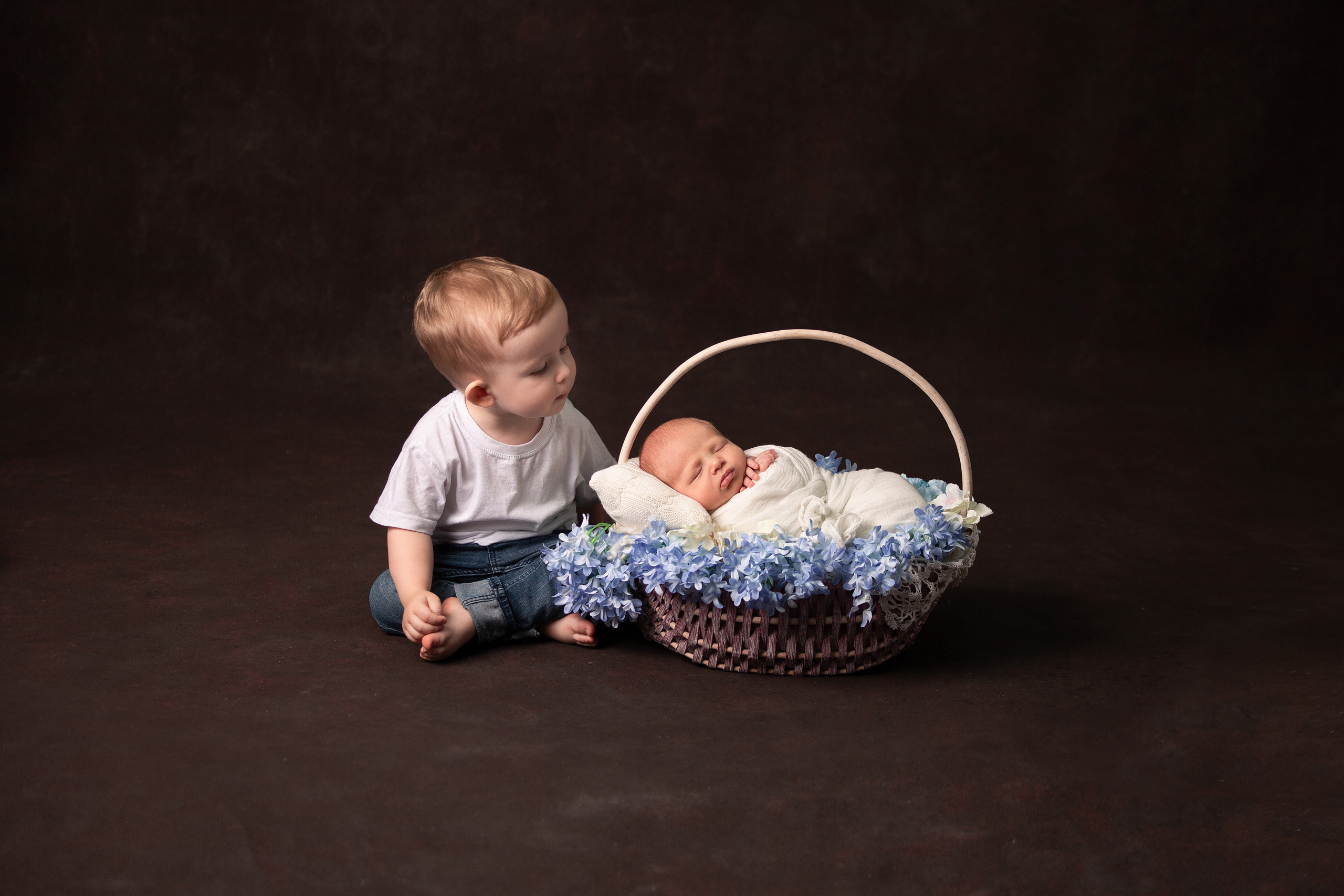 новорожденный малыш в корзинке с цветочками со страшим братом