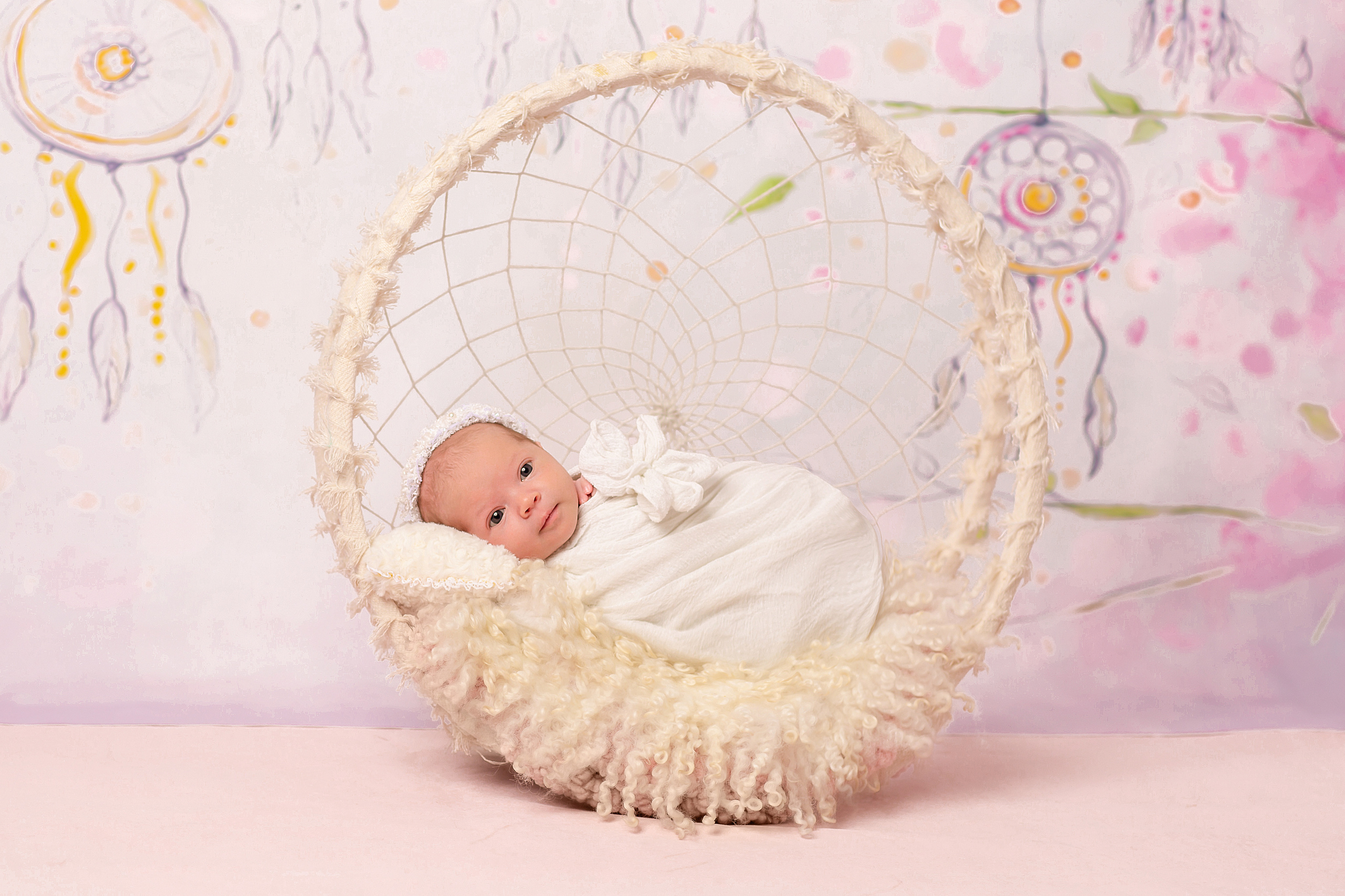 новорожденный малыш в корзинке на белом мехе с ловцом снов