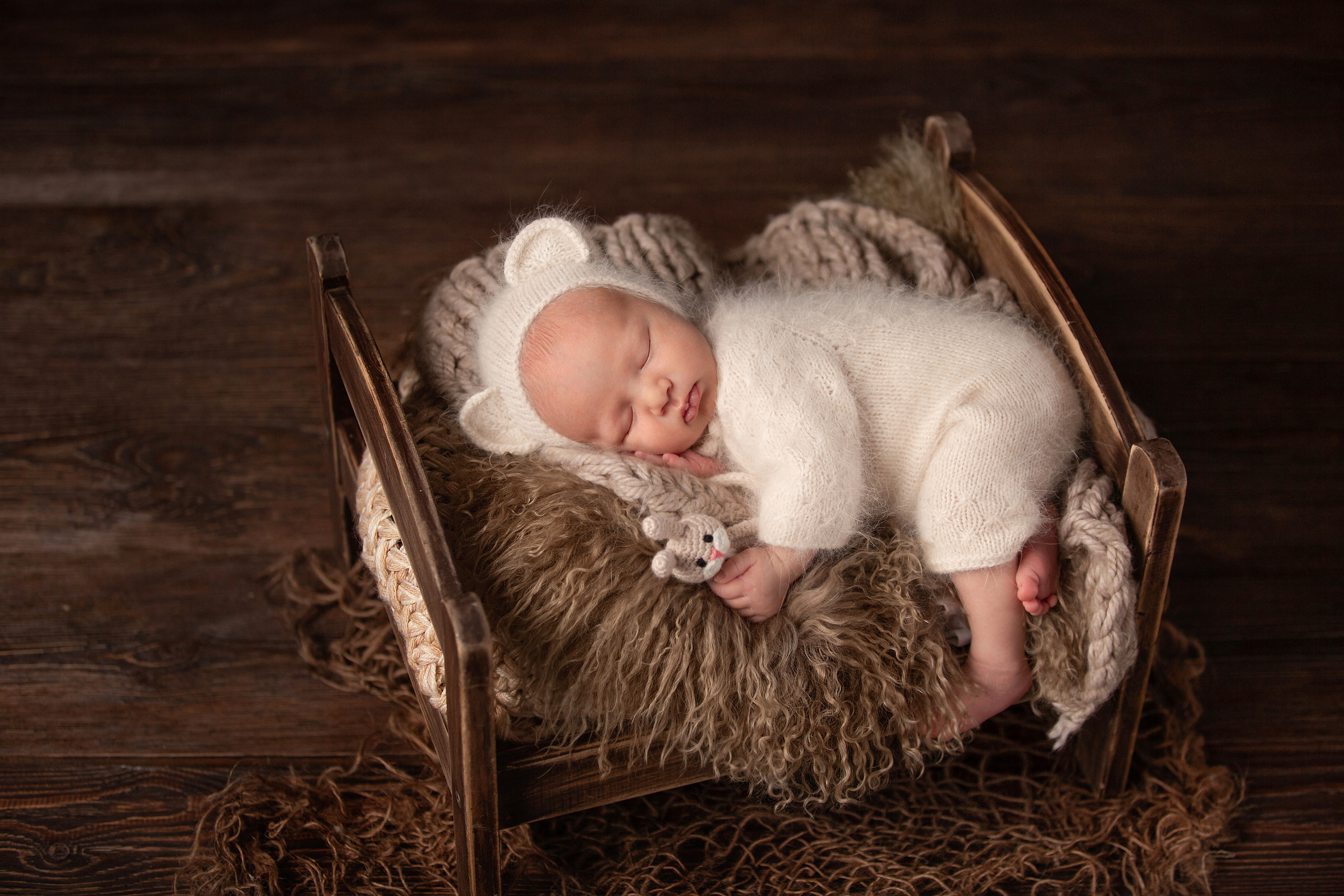 новорожденный малыш в белом пушистом костюме в детской кровати