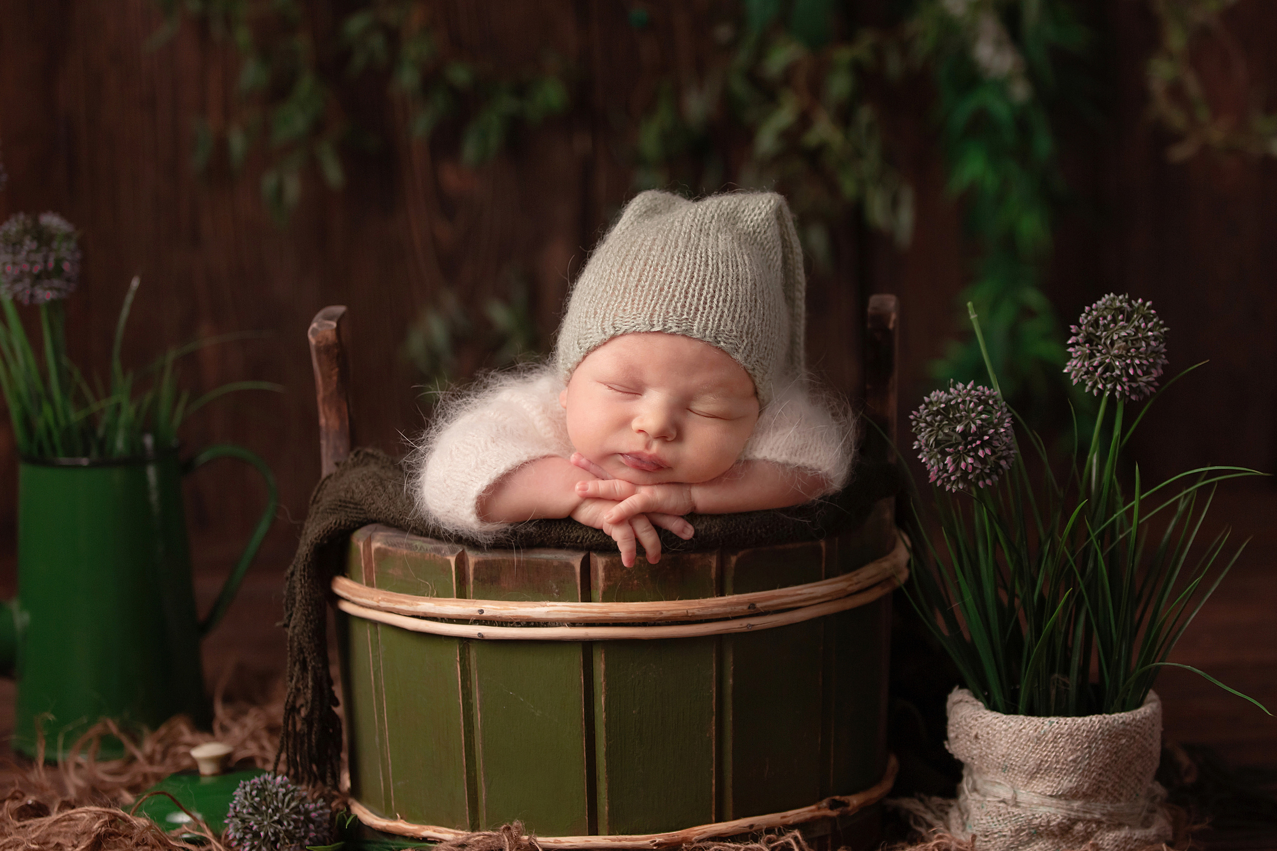 спящий новорожденный малыш в зеленой бадейке