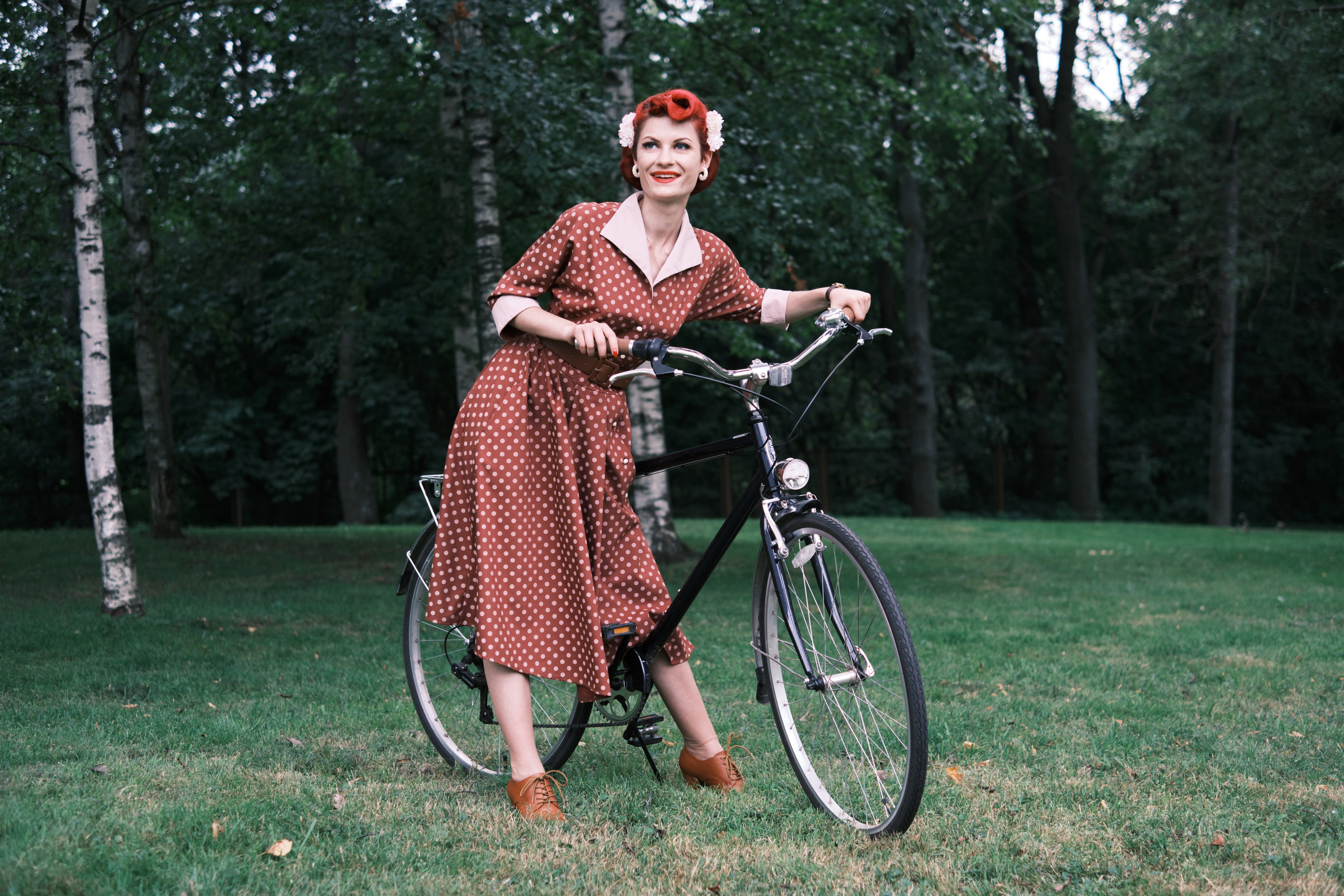 Девушка стоит на фоне деревьев с велосипедом