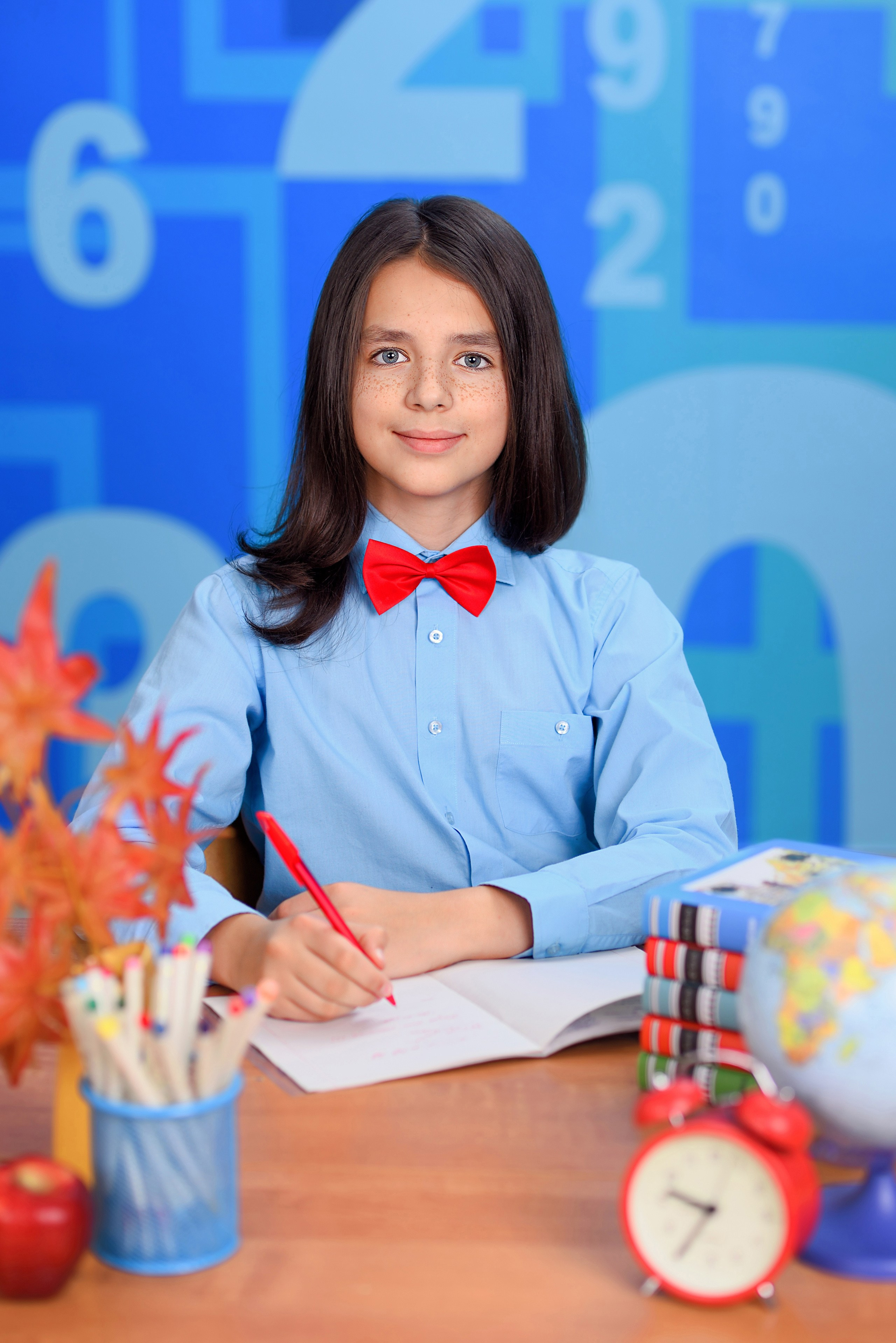 Классический портрет школьника за школьной партой, держащего шариковую ручку.