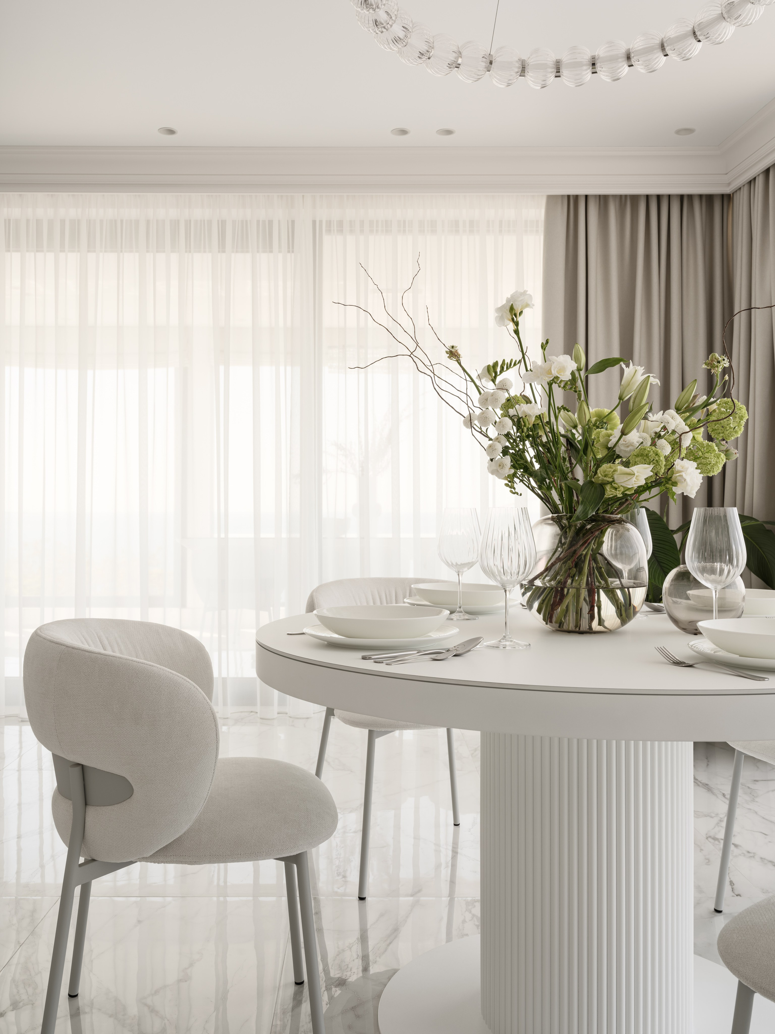 Деталь обеденной зоны с круглым столом на рифлёной опоре, посудой и цветочной композицией, отражение мягкого света от мраморного пола подчёркивает изящество пространства — дизайн Алёны Боярской, стилист Наталья Якушева, фото Сергей Денисенко.