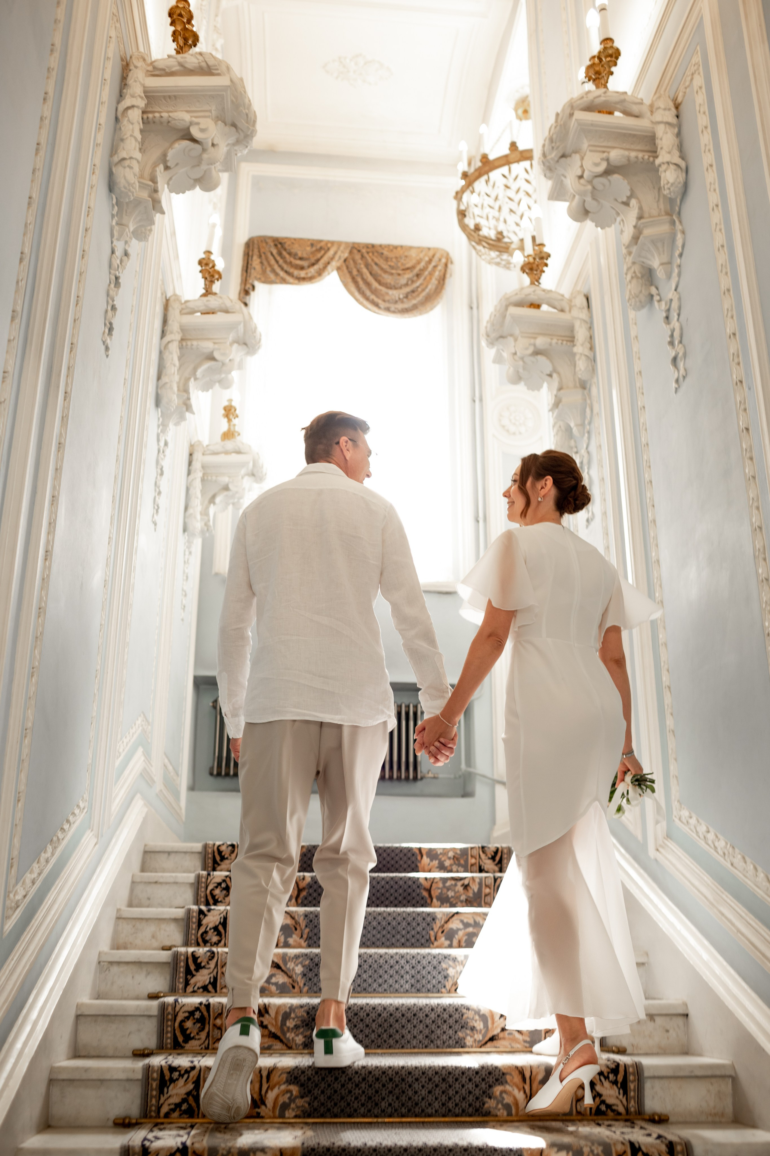 свадебный фотограф СПб, пара держится за руки на лестнице ЗАГСа