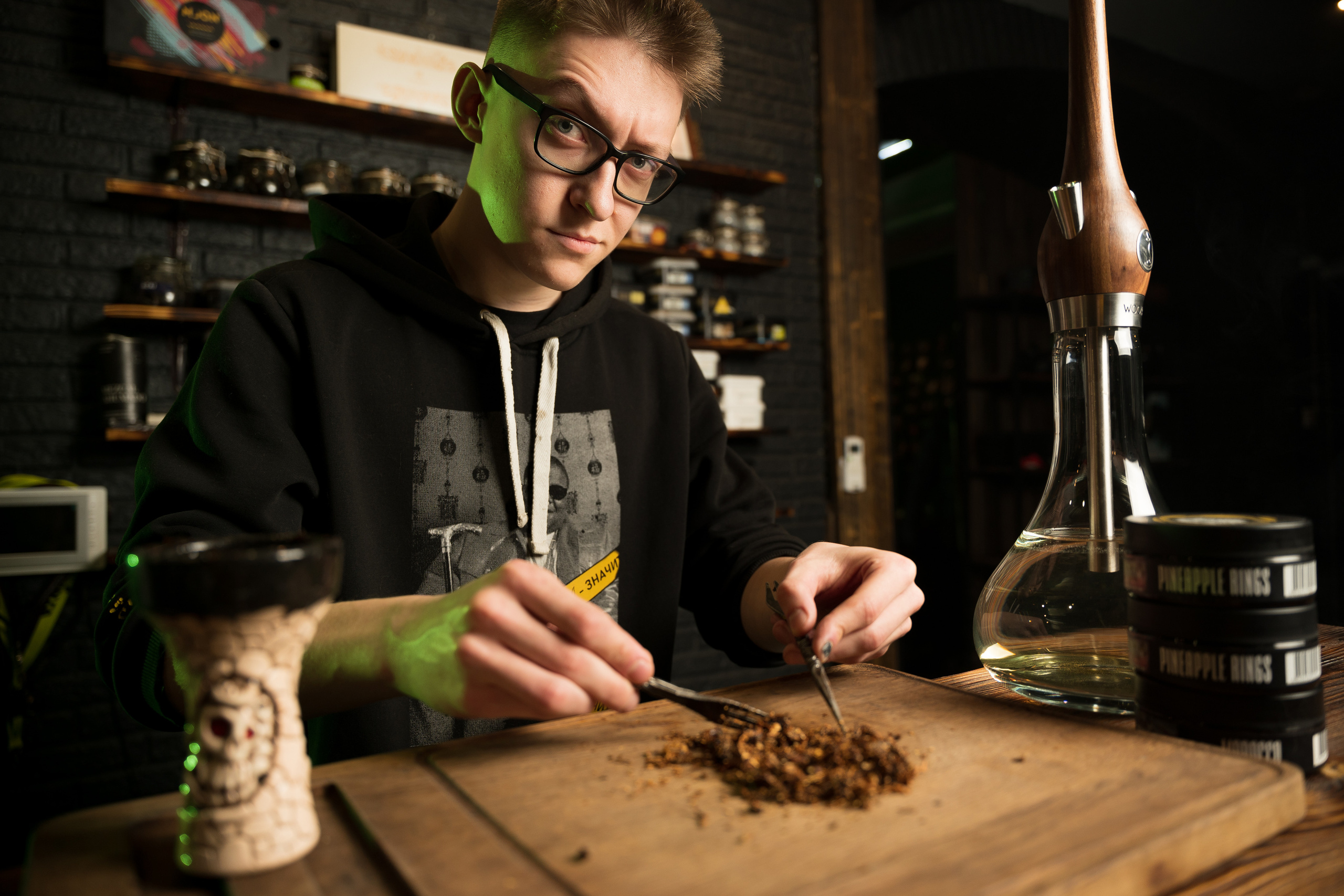 Family Community Нижний Новгород Фотосъемка персонала. Молодой человек мужчина парень кальянщик в очках готовит табак для кальяна в кальянной.