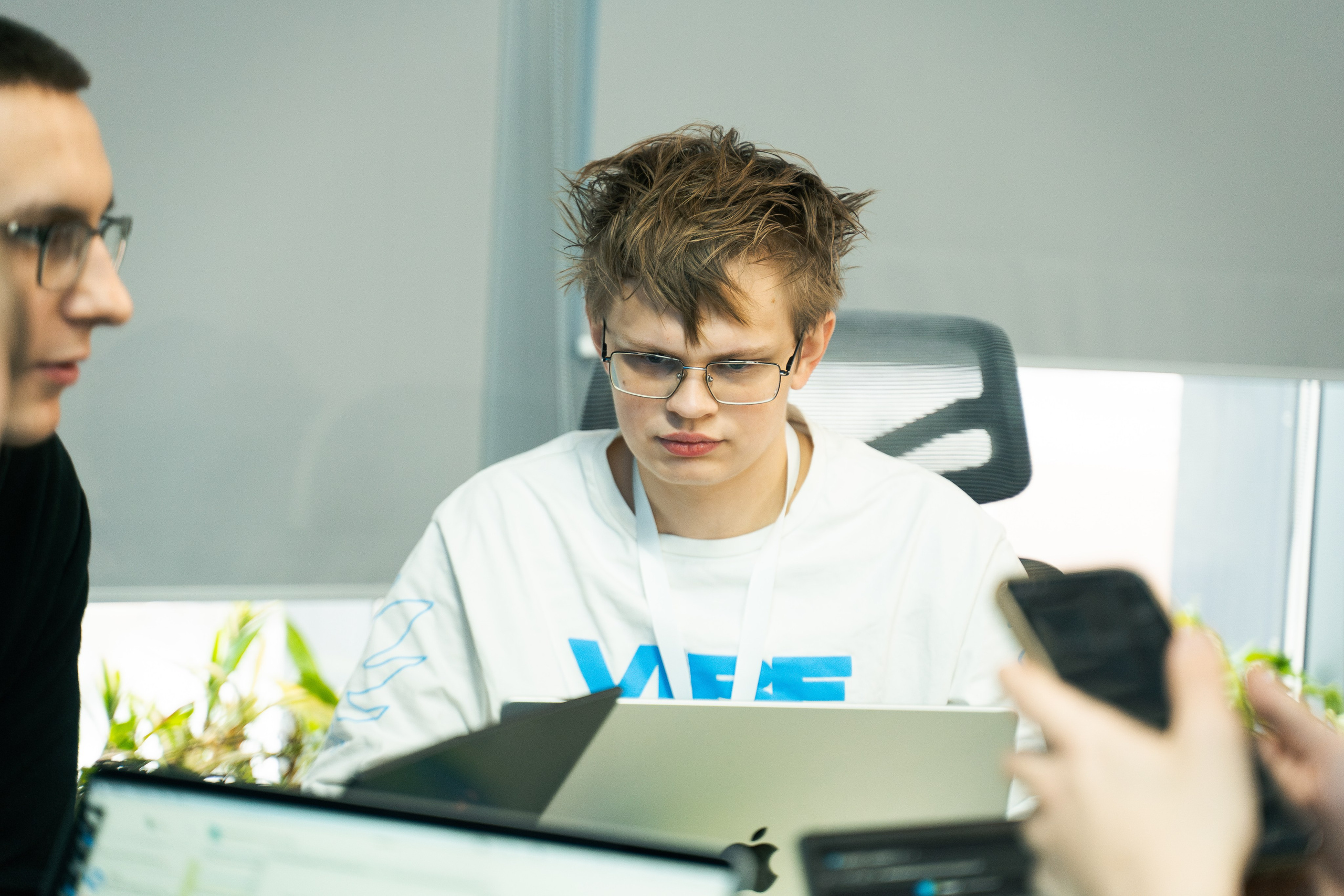 Участник пишет код на ноутбуке в ярко освещенной рабочей зоне