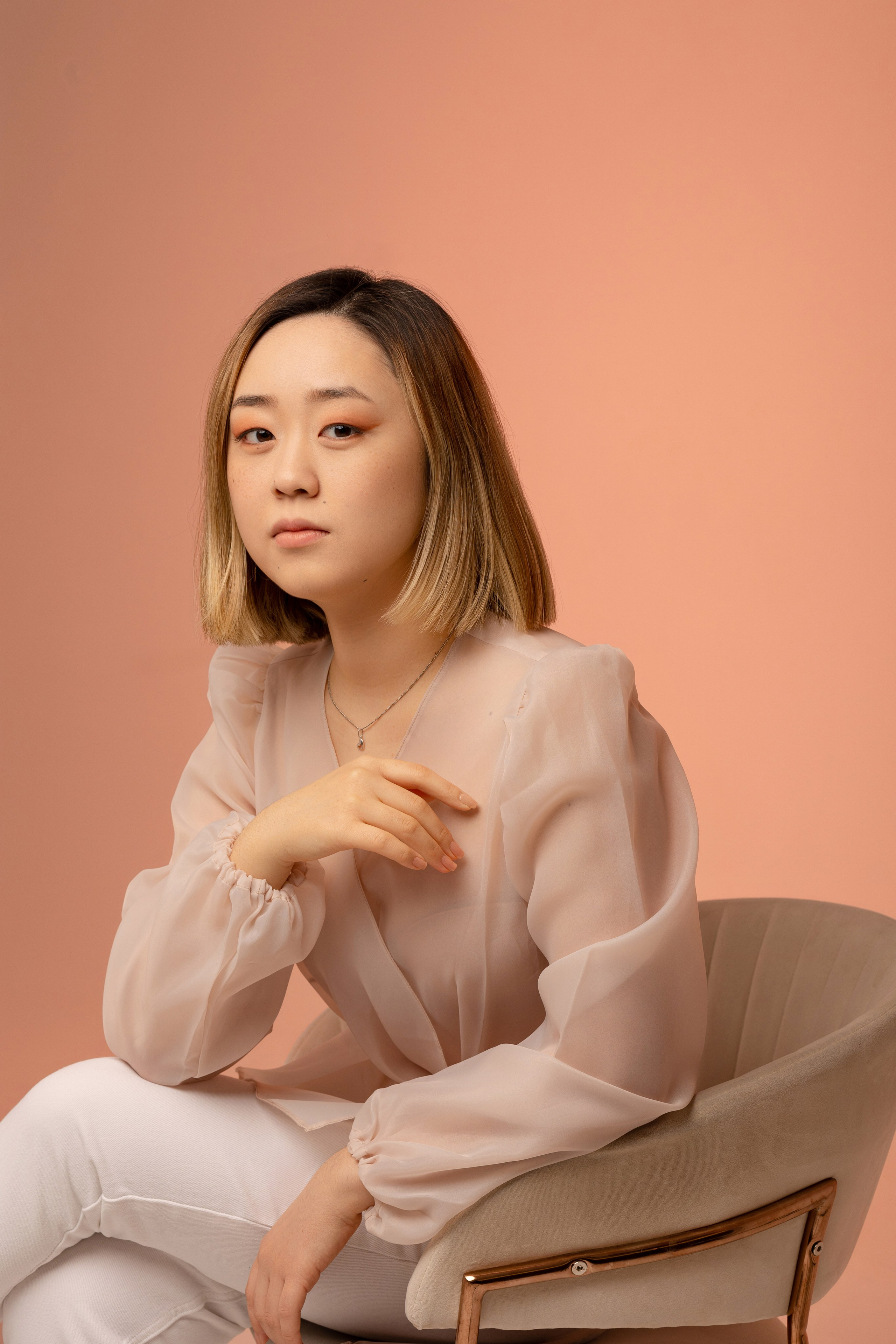 Девушка сидит в кресле левая рука на подлокотнике.