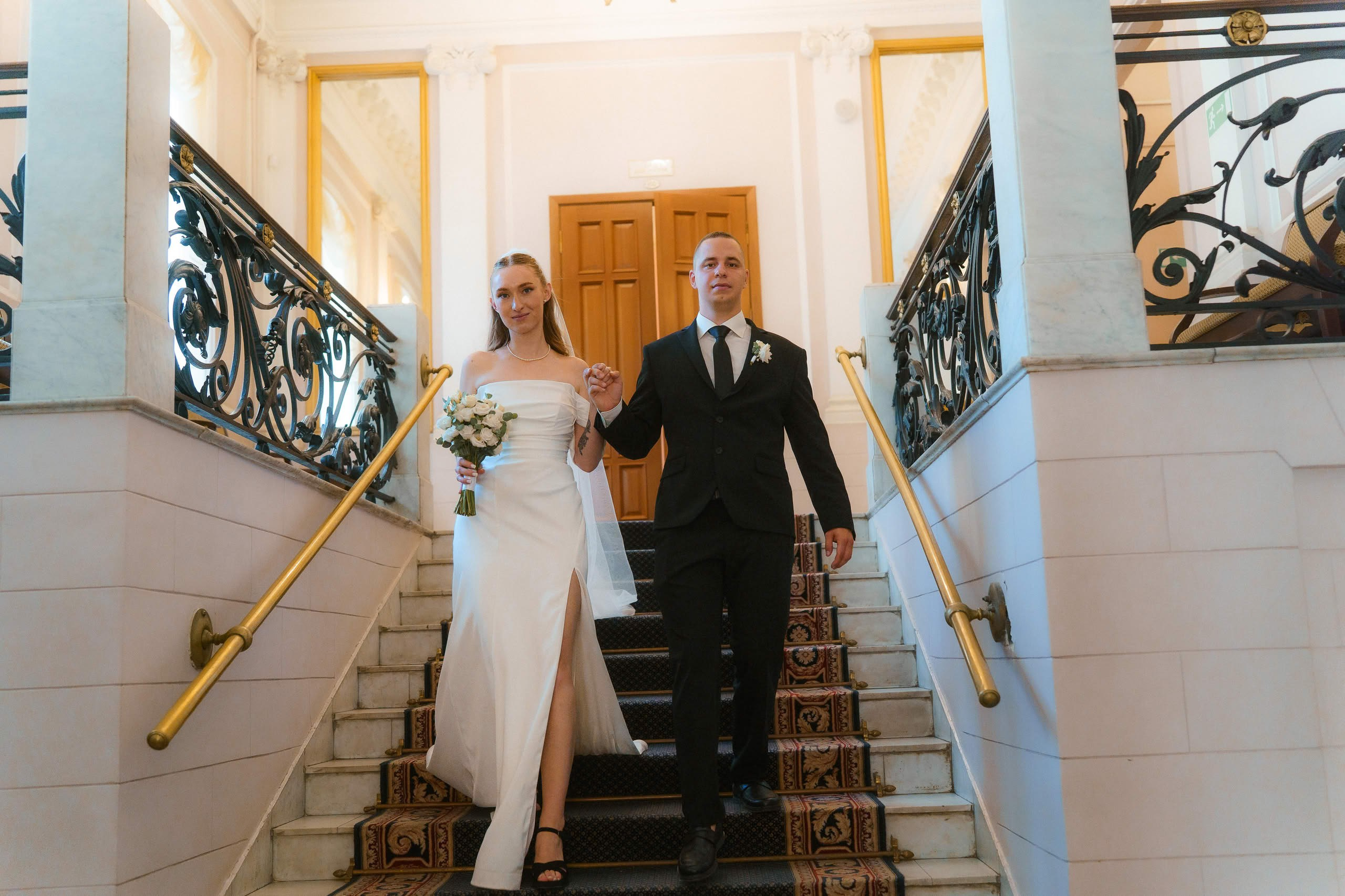 Жених и невеста спускаются по лестнице ЗАГСа Петроградского района  