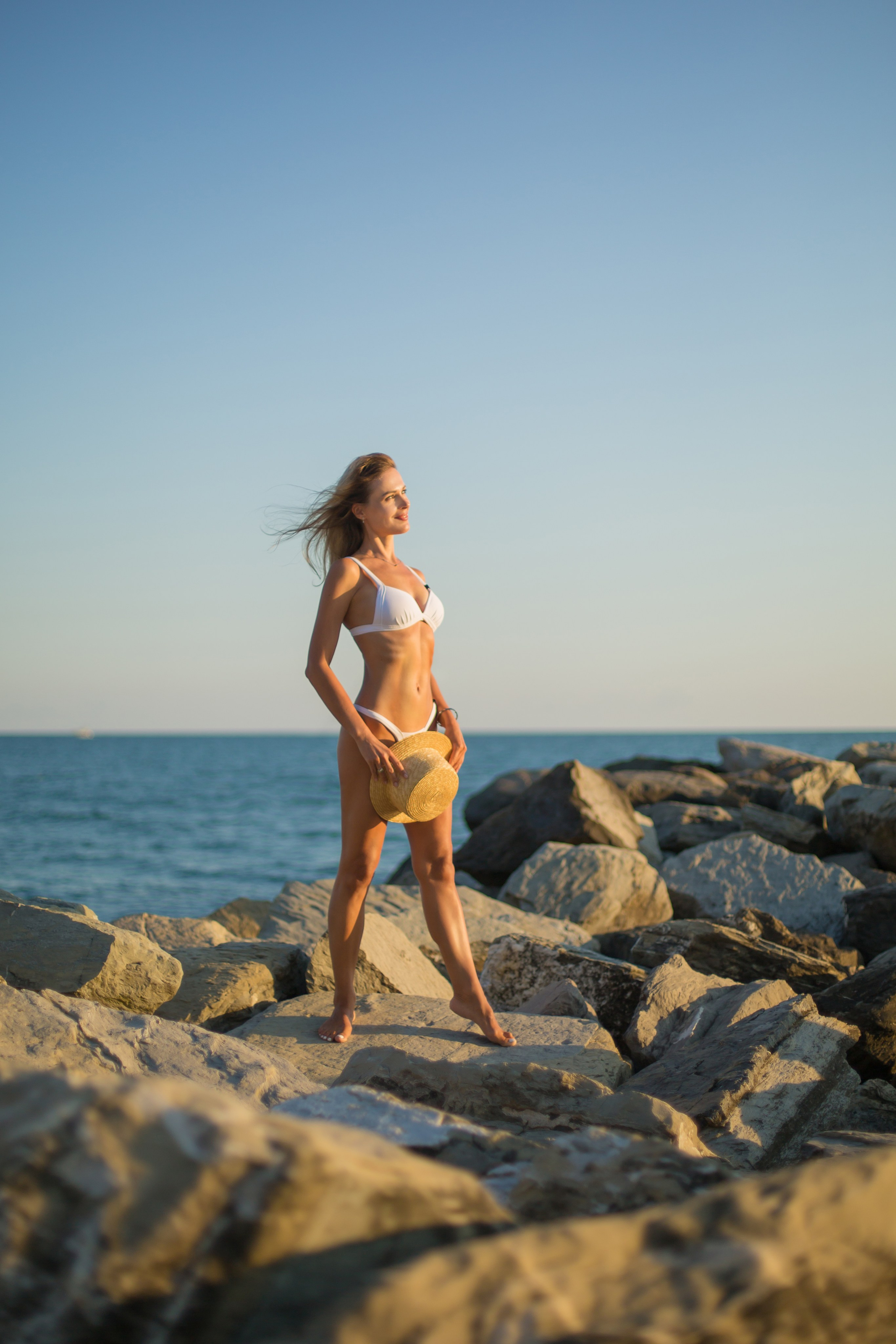 девушка в белом купальнике стоит у моря