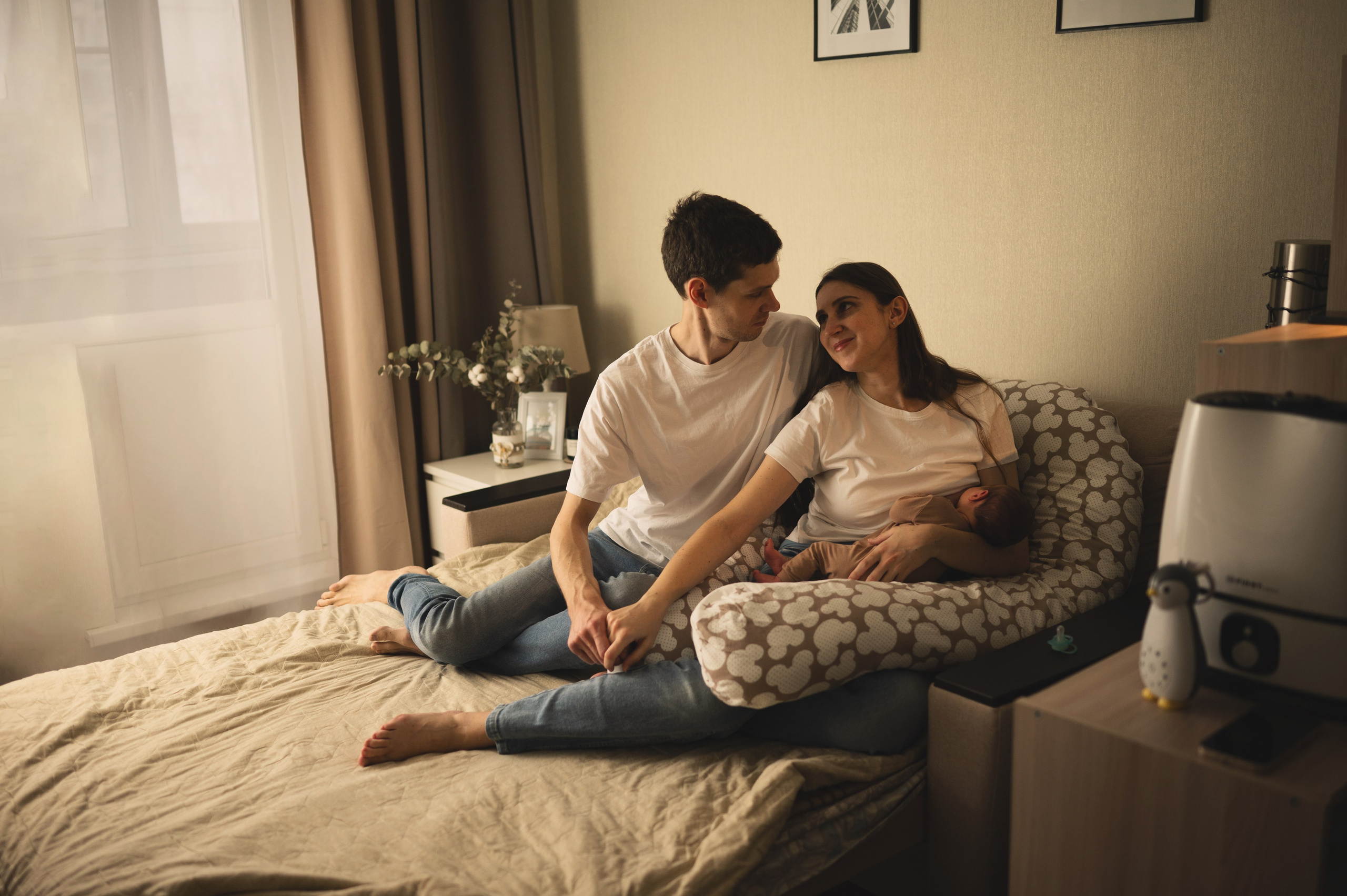 Молодые родители обнимают новорожденного малыша 