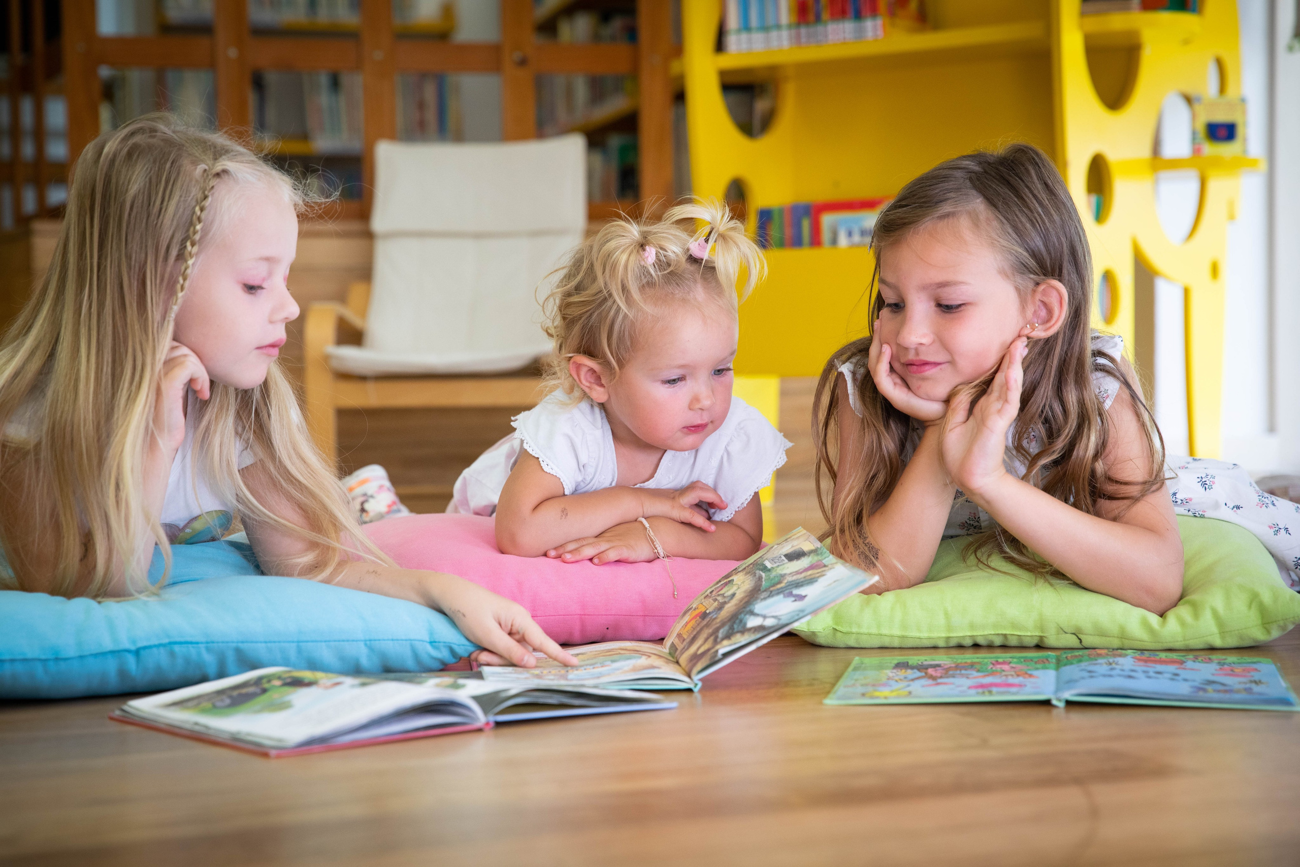 Sunlight streams through the windows, as children happily read and play in the library