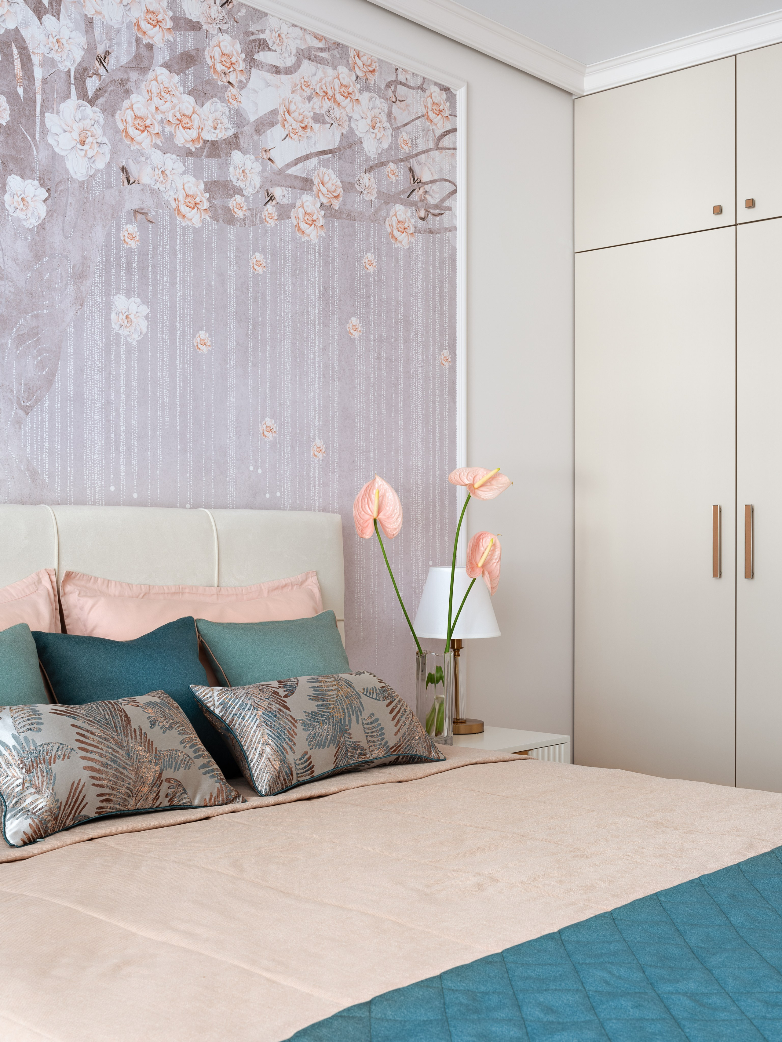 Современная спальня с нежными обоями с цветущим деревом, лаконичным шкафом с гладкими фасадами, кроватью в пастельных тонах и текстилем в бирюзовых акцентах. Интерьер разработан дизайнером Натальей Бунеевой, стилизован Натальей Якушевой и запечатлён фотографом Сергеем Денисенко.