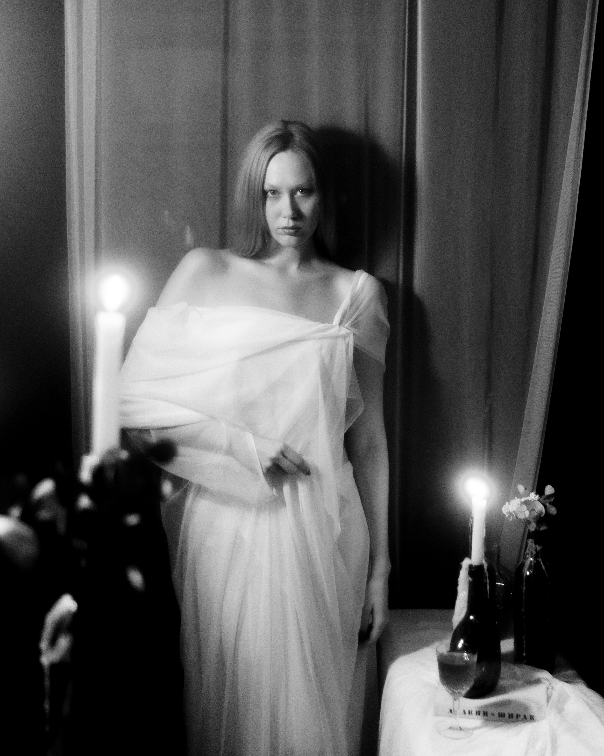 Черно-белая авторская фотосессия девушки в полный рост, белая ткань, свечи и драматичный студийный портрет