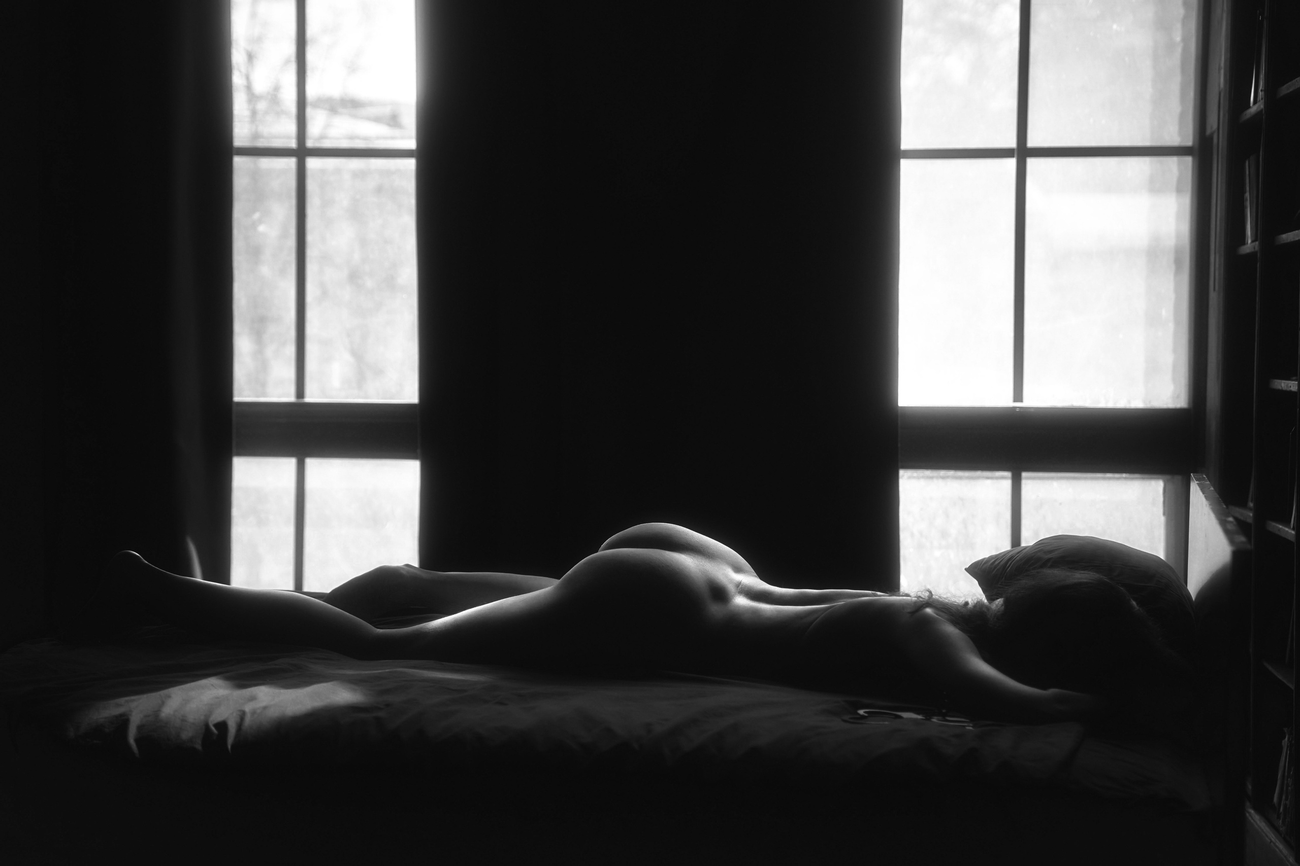 девушка лежит на кровати во время фотосессии у ню фотографа