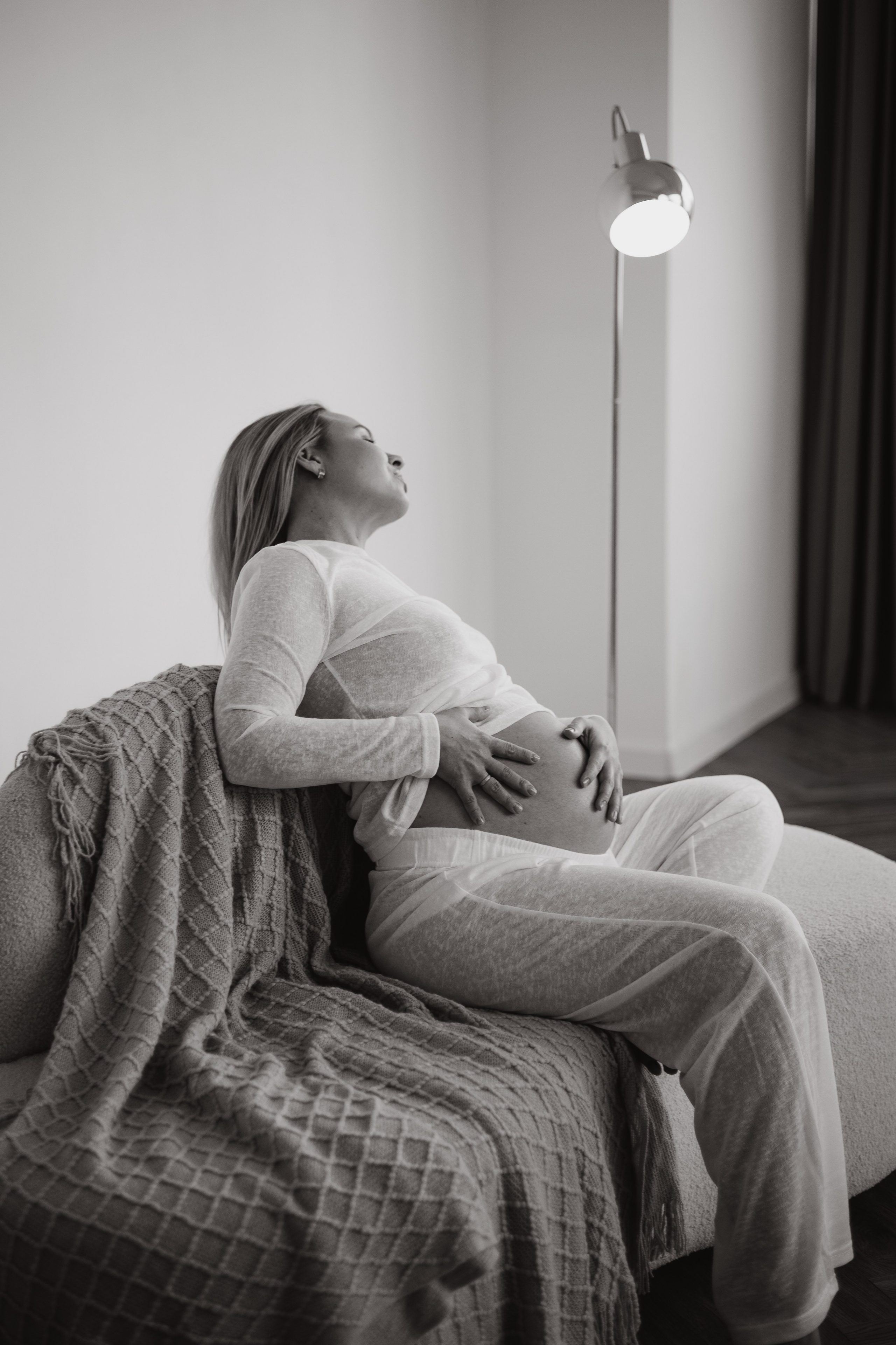 Фото ожидания малыша: будущая мама сидит, поджав ноги, и читает книгу малышу, ее живот красиво округлился на 28 неделе.