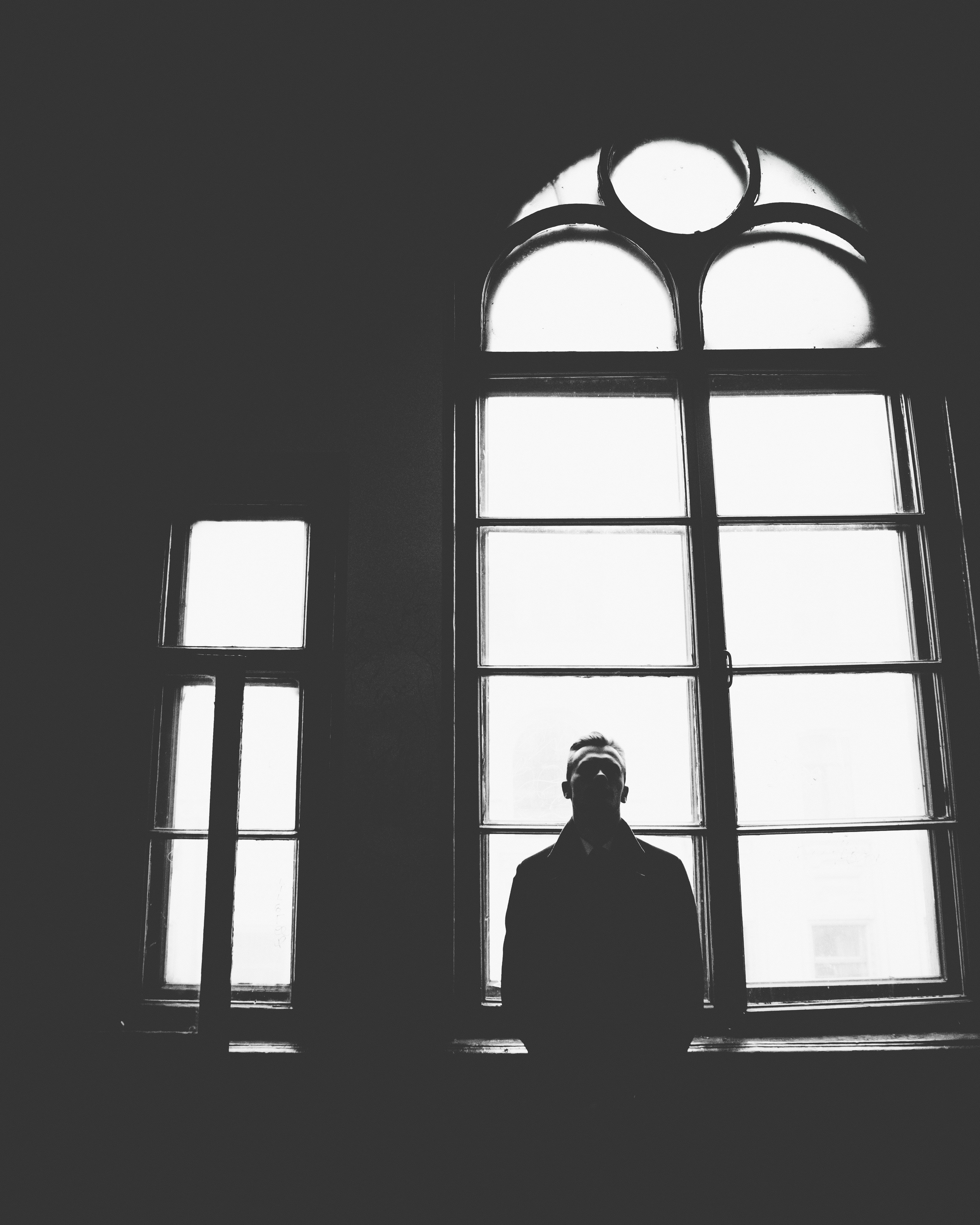 Мужчина в костюме на фоне окна в контровом свете в одной из парадных санкт-петербурга