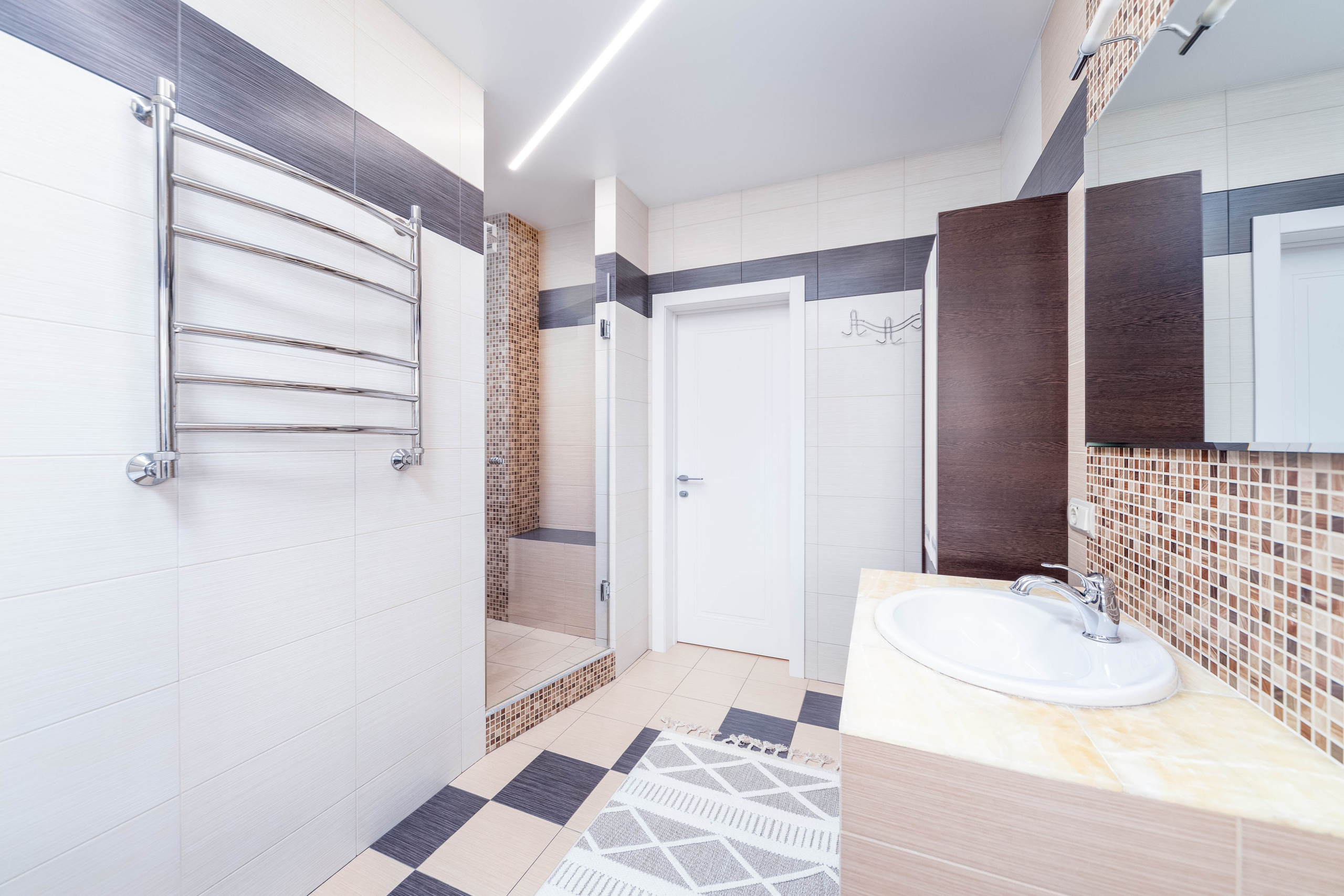 Полотенцесушитель, раковина и стеклянна душевая кабина в санузле