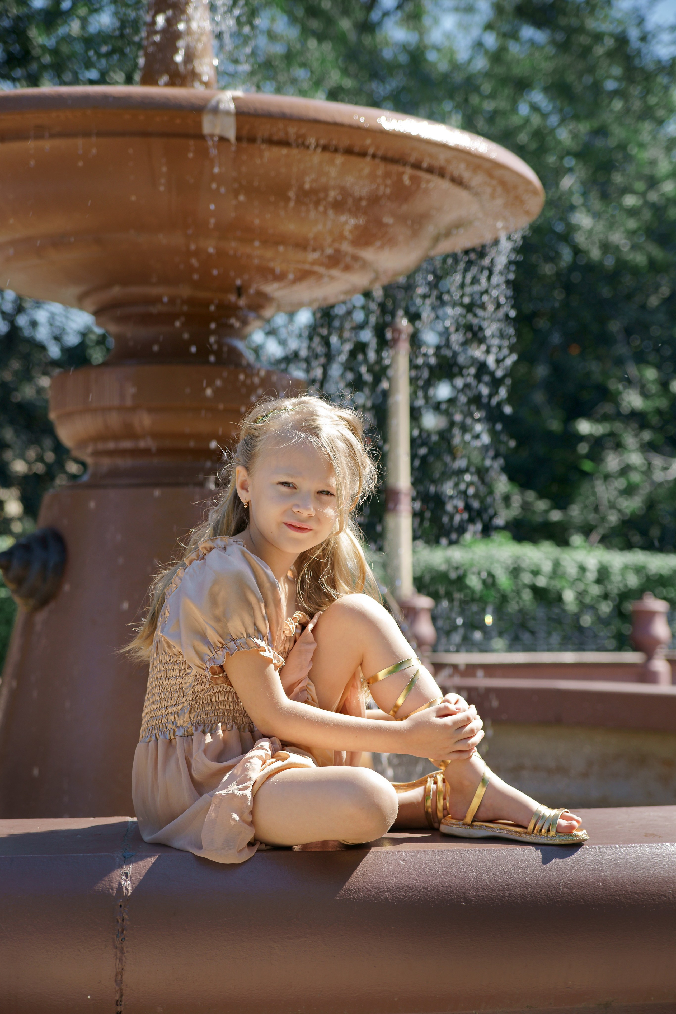 Детская фотосессия летом - девочка сидя у фонтана в греческом стиле