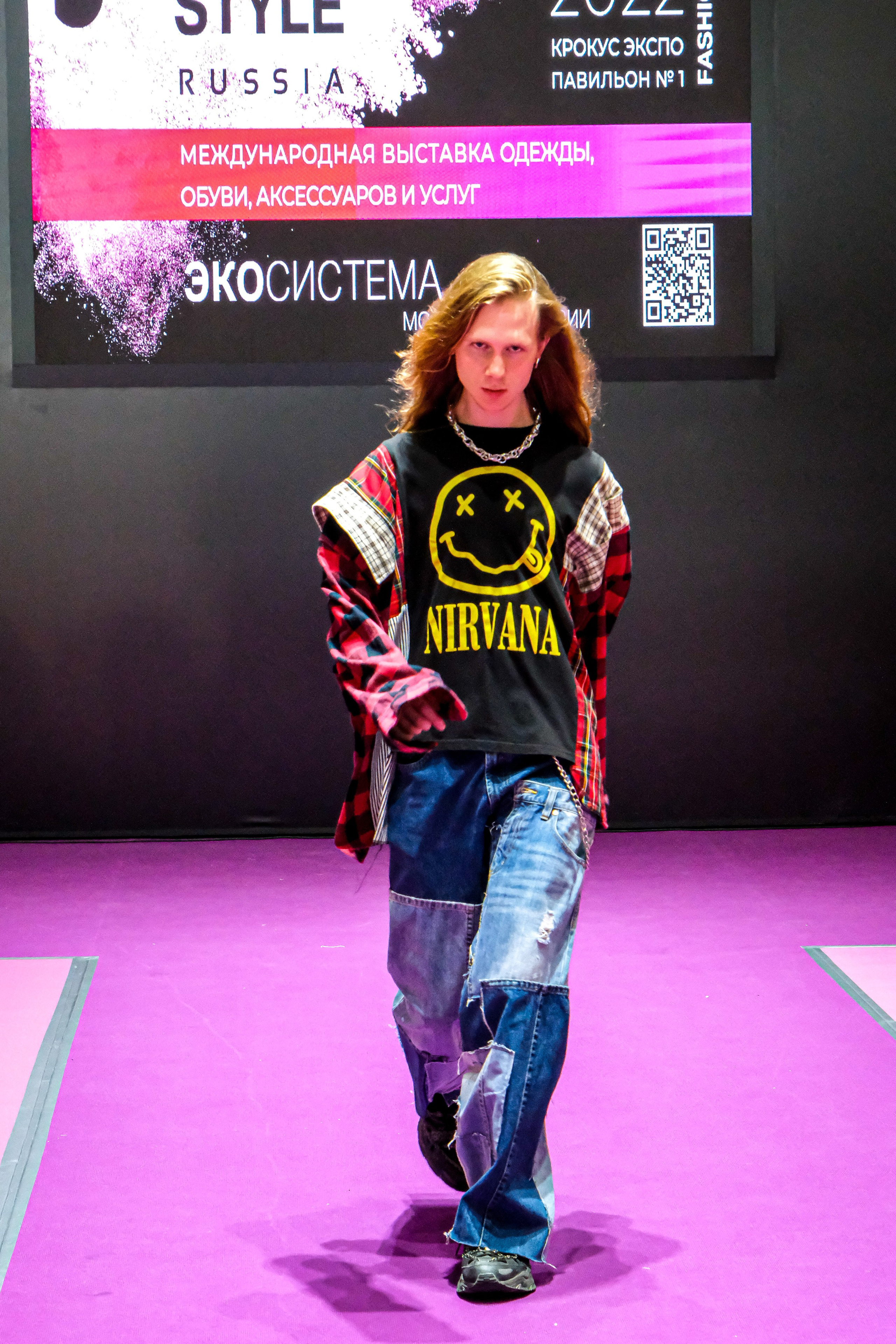  "Модели в ярких нарядах проходят по подиуму во время показа мод, освещенные яркими софитами и окруженные восторженными зрителями."