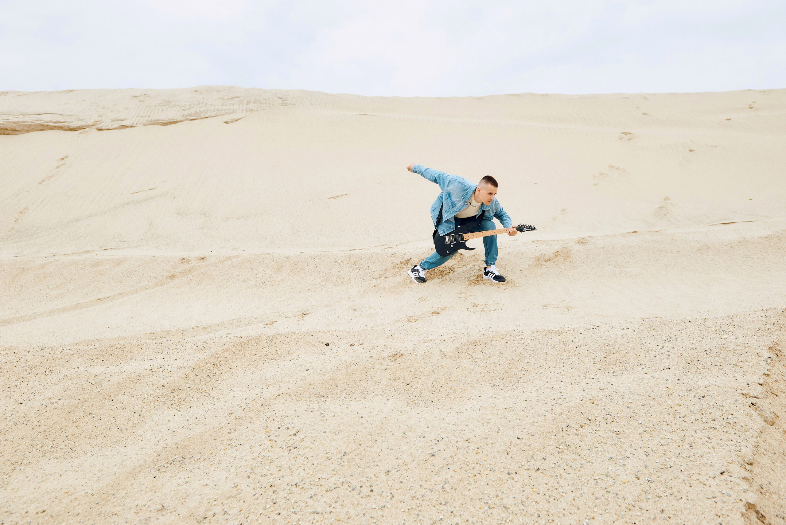 Парень играет на гитаре в пустыне