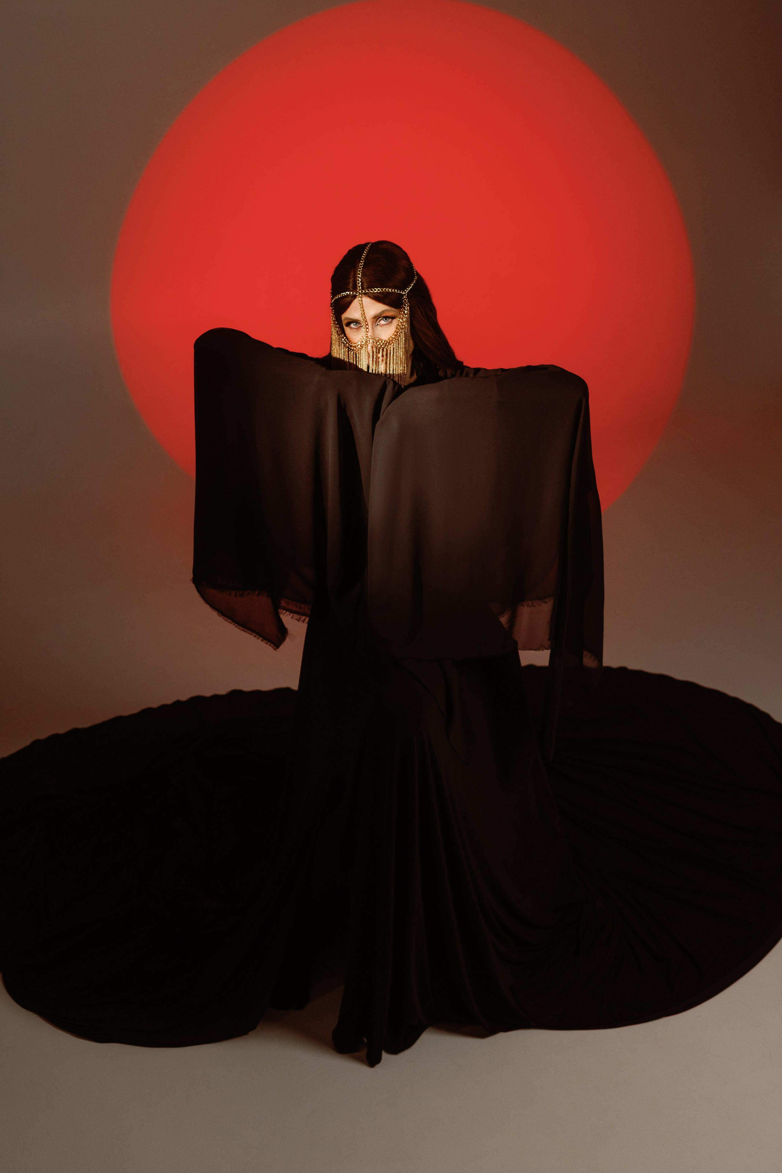 На фотографии изображена девушка в хиджабе позади нее луч света напоминающий солнце, фотосессия в сутдии в восточном стиле