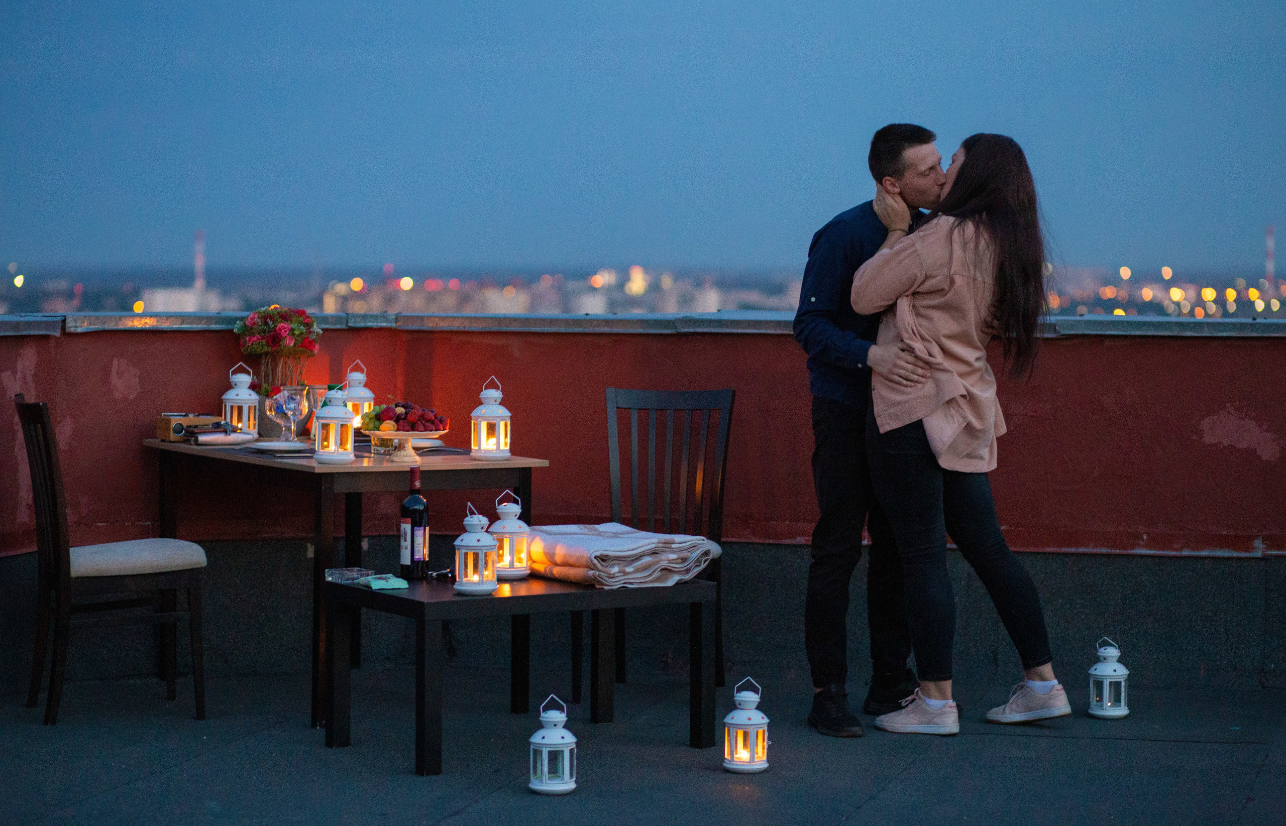 свидание на  крыше  Воронежа. молодой человек  и девушка проводят романтический  вечер на  крыше. вокруг  горят свечи.
