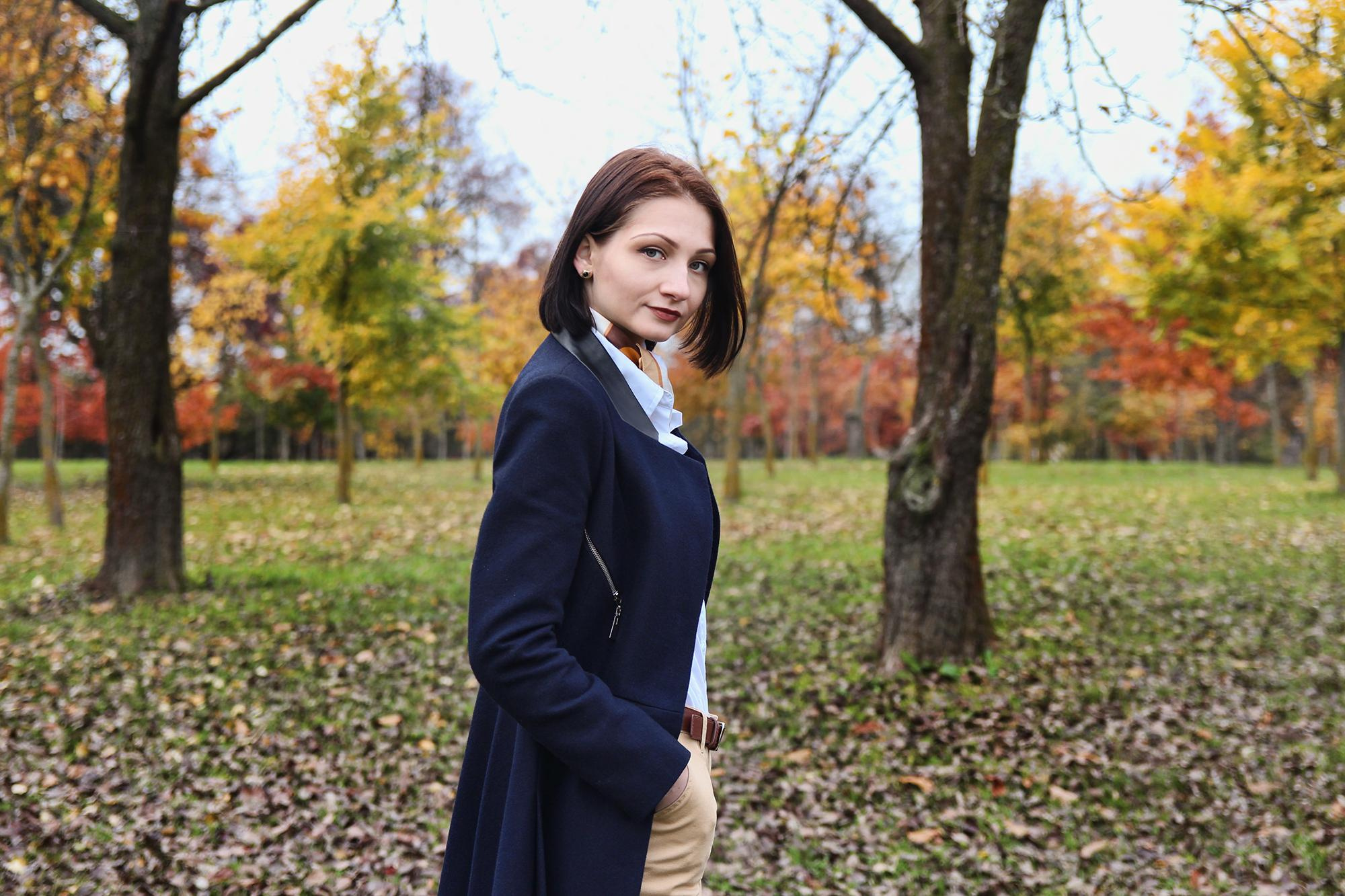 молодая брюнетка в черном пальто в осеннем сквере