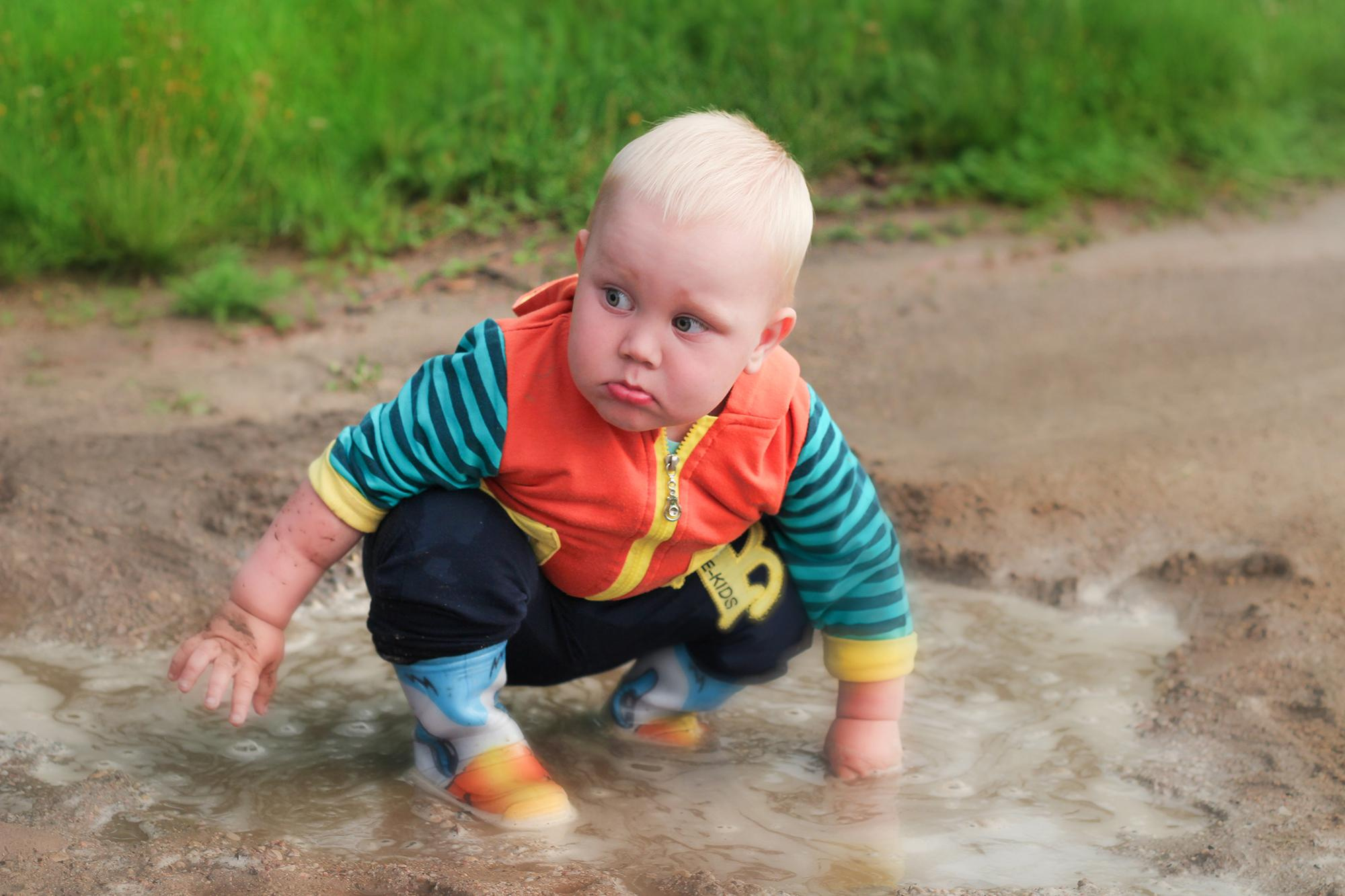малыш ковыряется в грязной луже