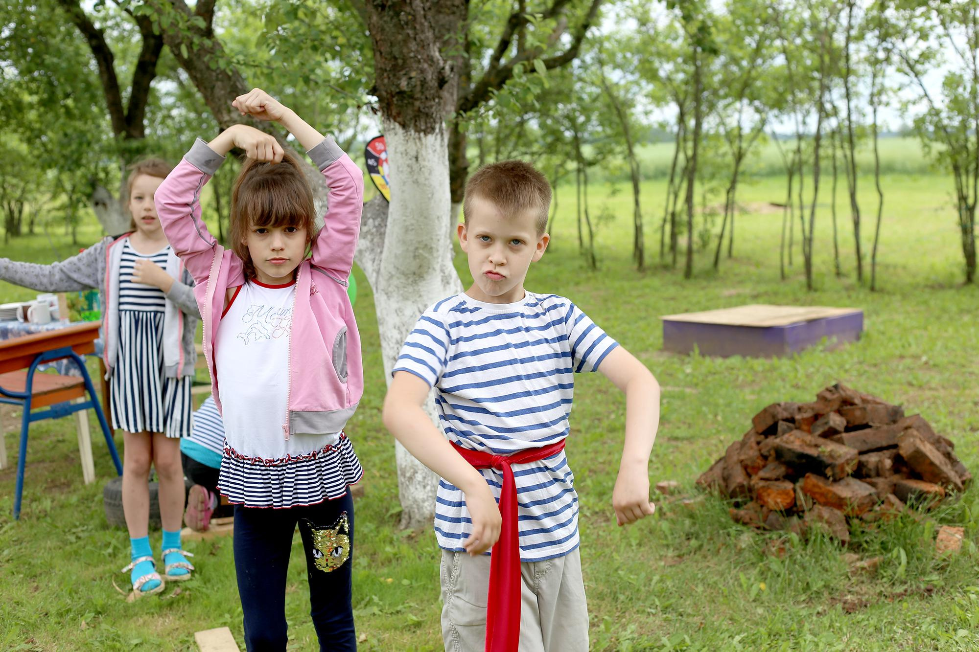 девочка и мальчик в полосатой одежде танцуют на улице