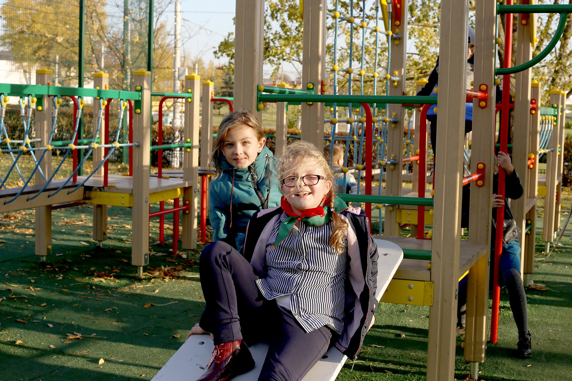 девочка в очках катается во дворе на горке