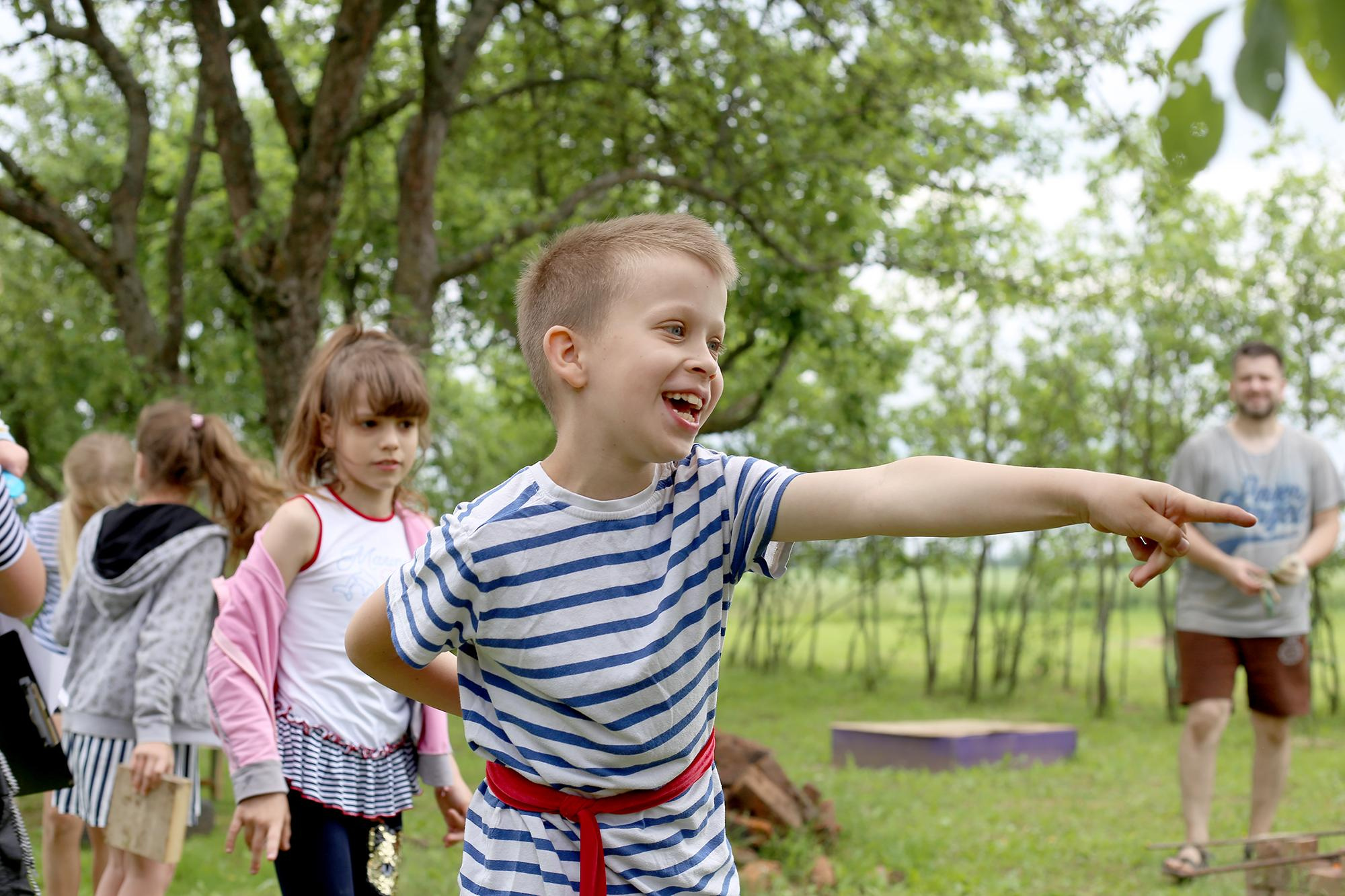 радостный мальчик в полосатой майке указывает в сторону