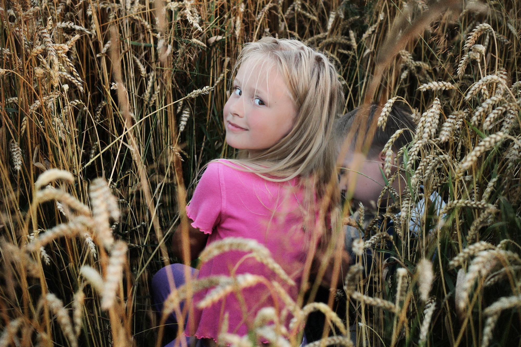 лохматая девочка в розовой майке прячется в поле