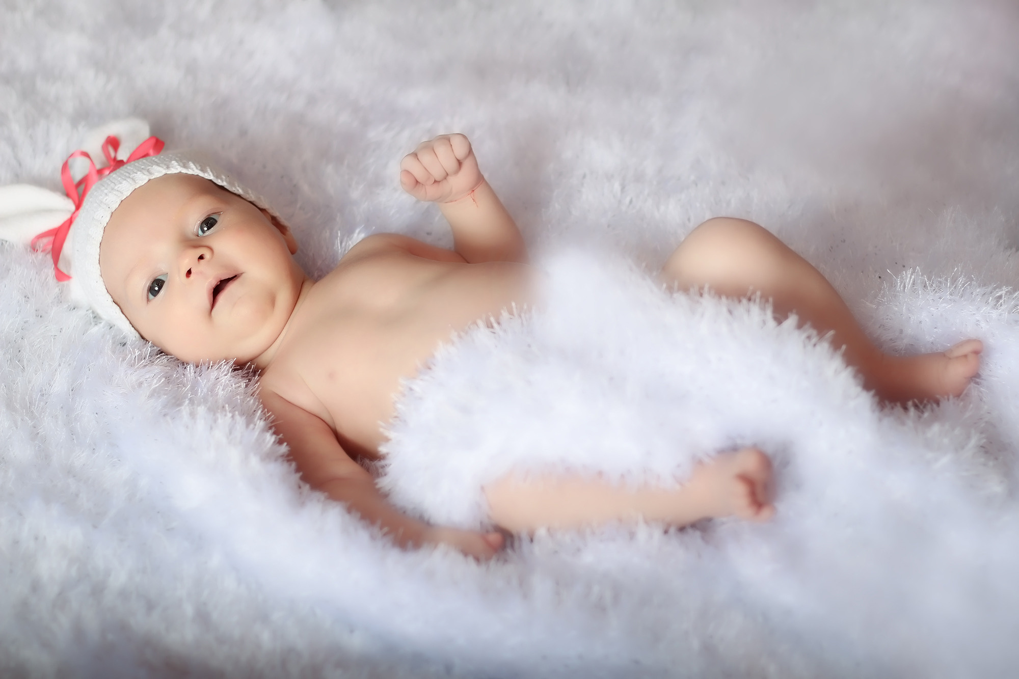 крошка в белой шапочке с ушками и розовыми ленточками