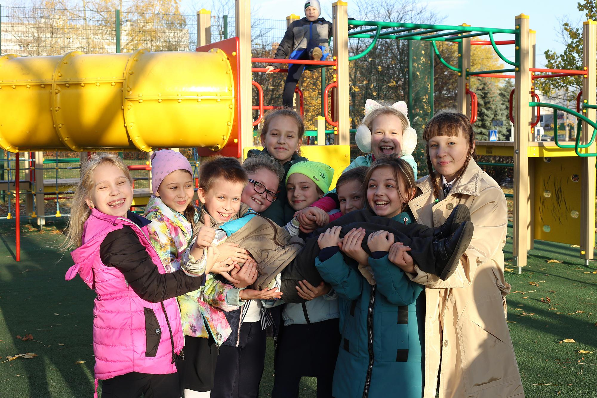 веселые девочки держат на руках маленького одноклассника