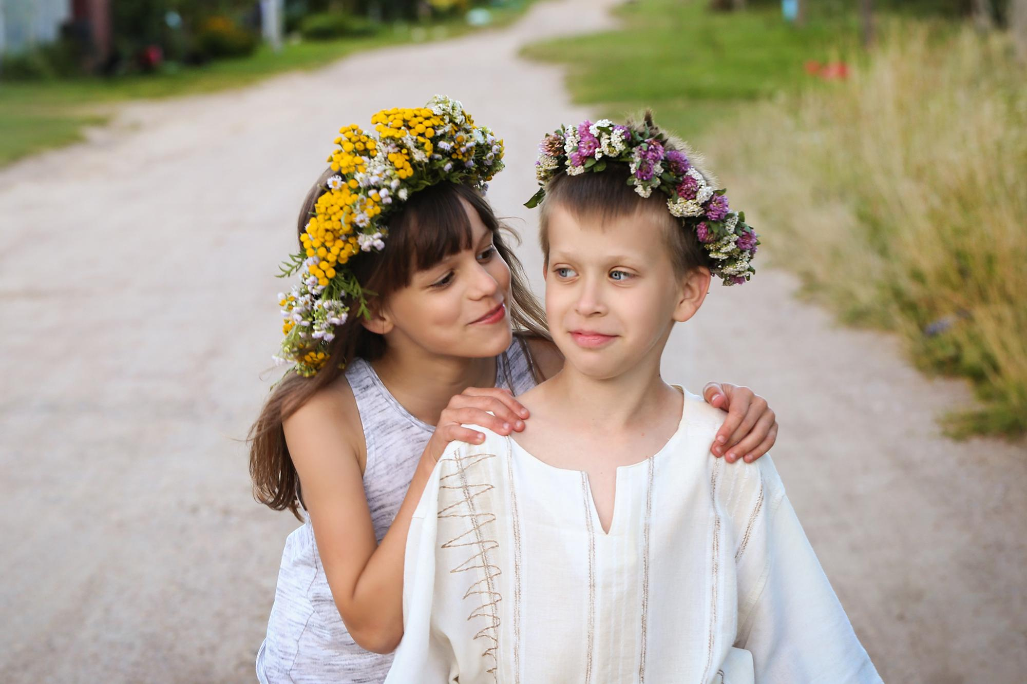 девочка и мальчик в цветочных венках на проселочной дороге